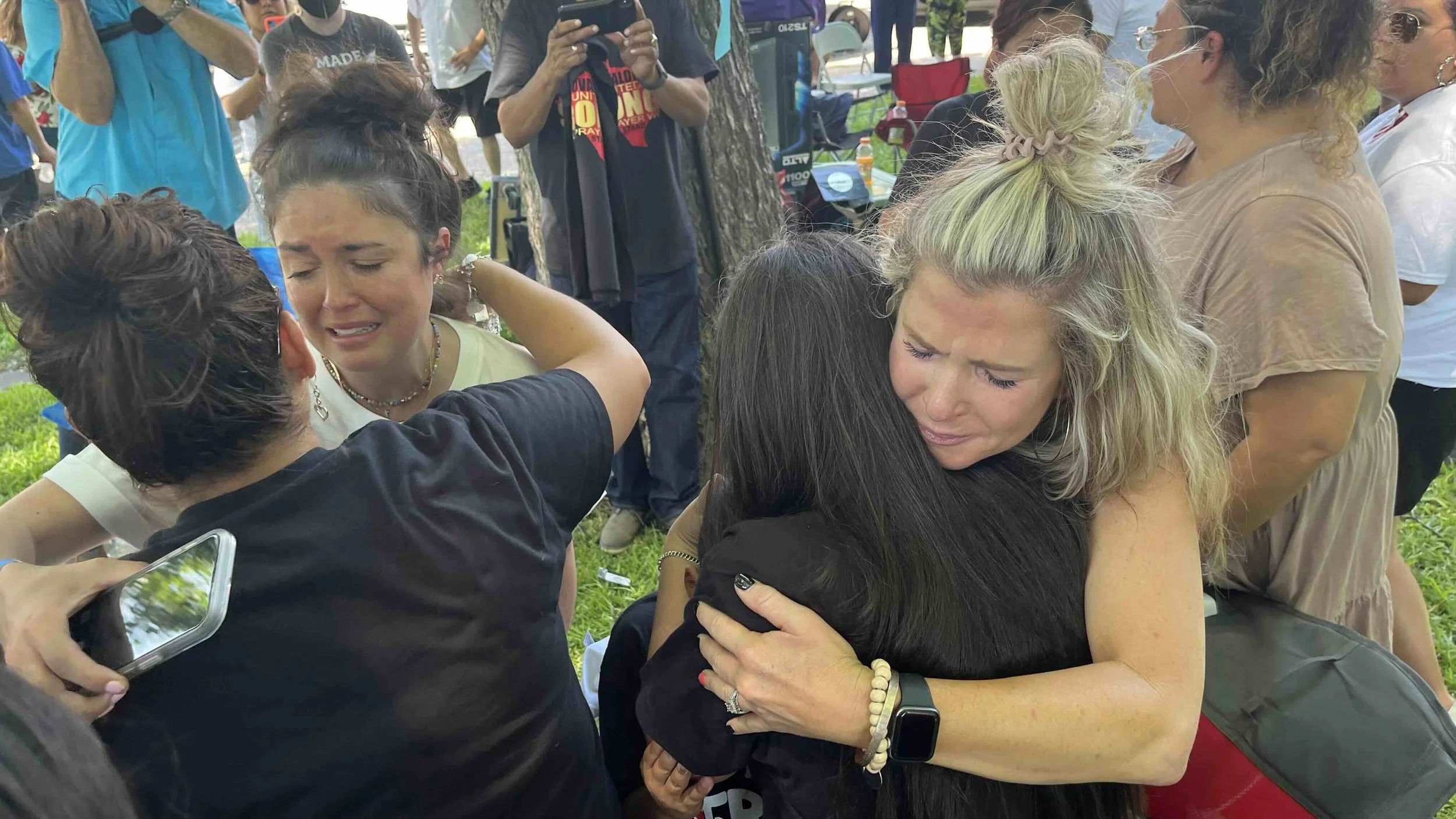 People embracing and comforting each other during an outdoor gathering