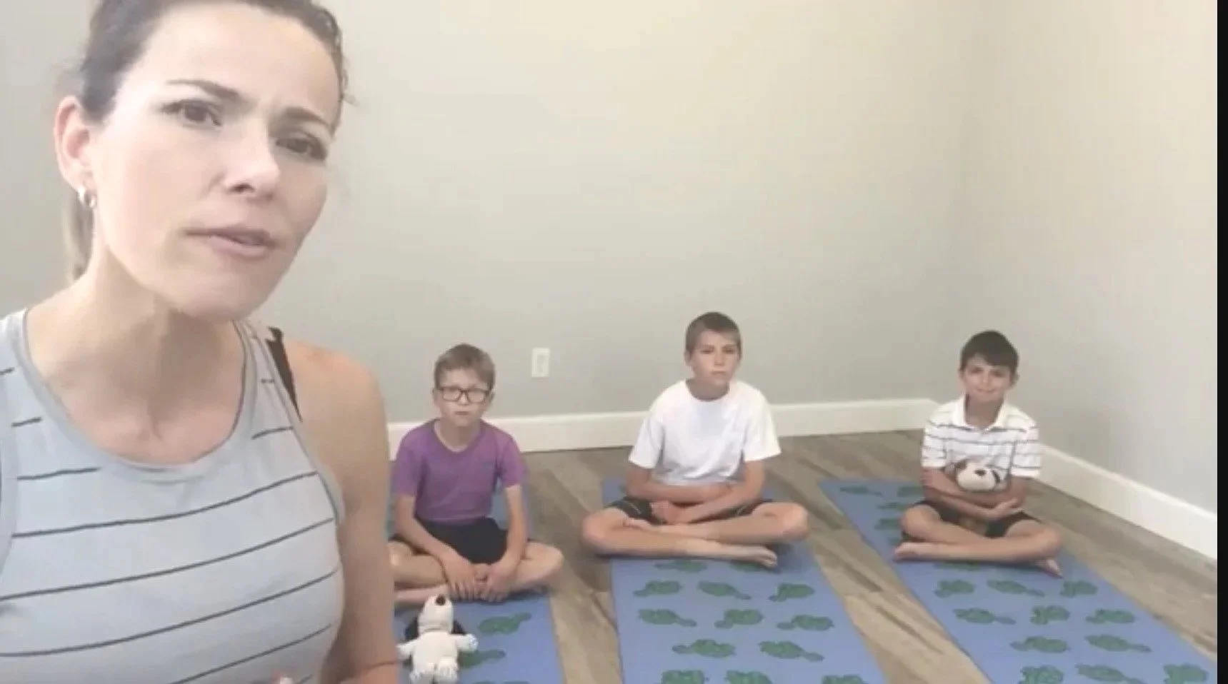 a yoga teacher looking at a computer and 3 small boys in a yoga mat ready to practice kids yoga