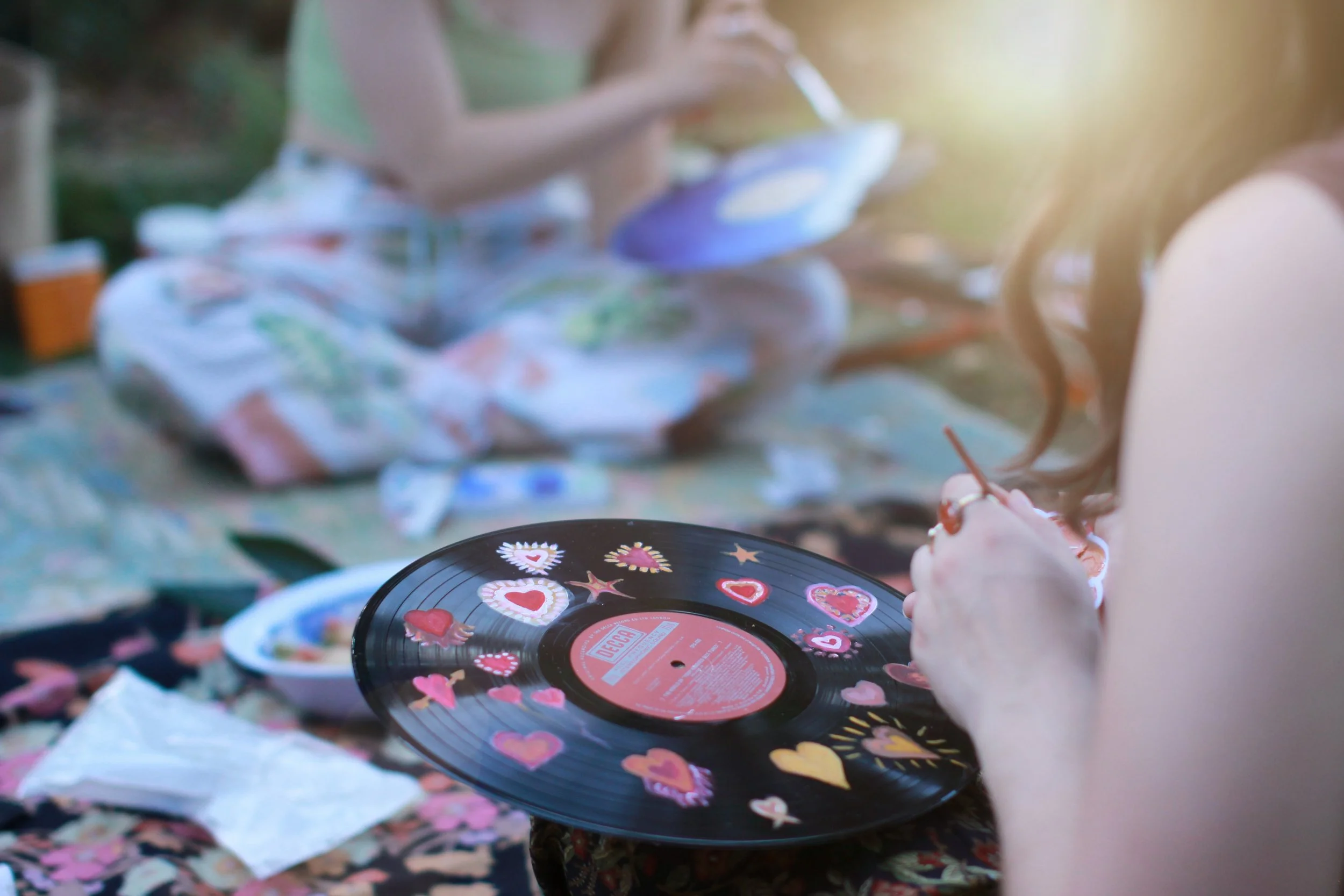 Behind-the-scenes of a vinyl painting workshop, with participants painting on repurposed vinyl records.