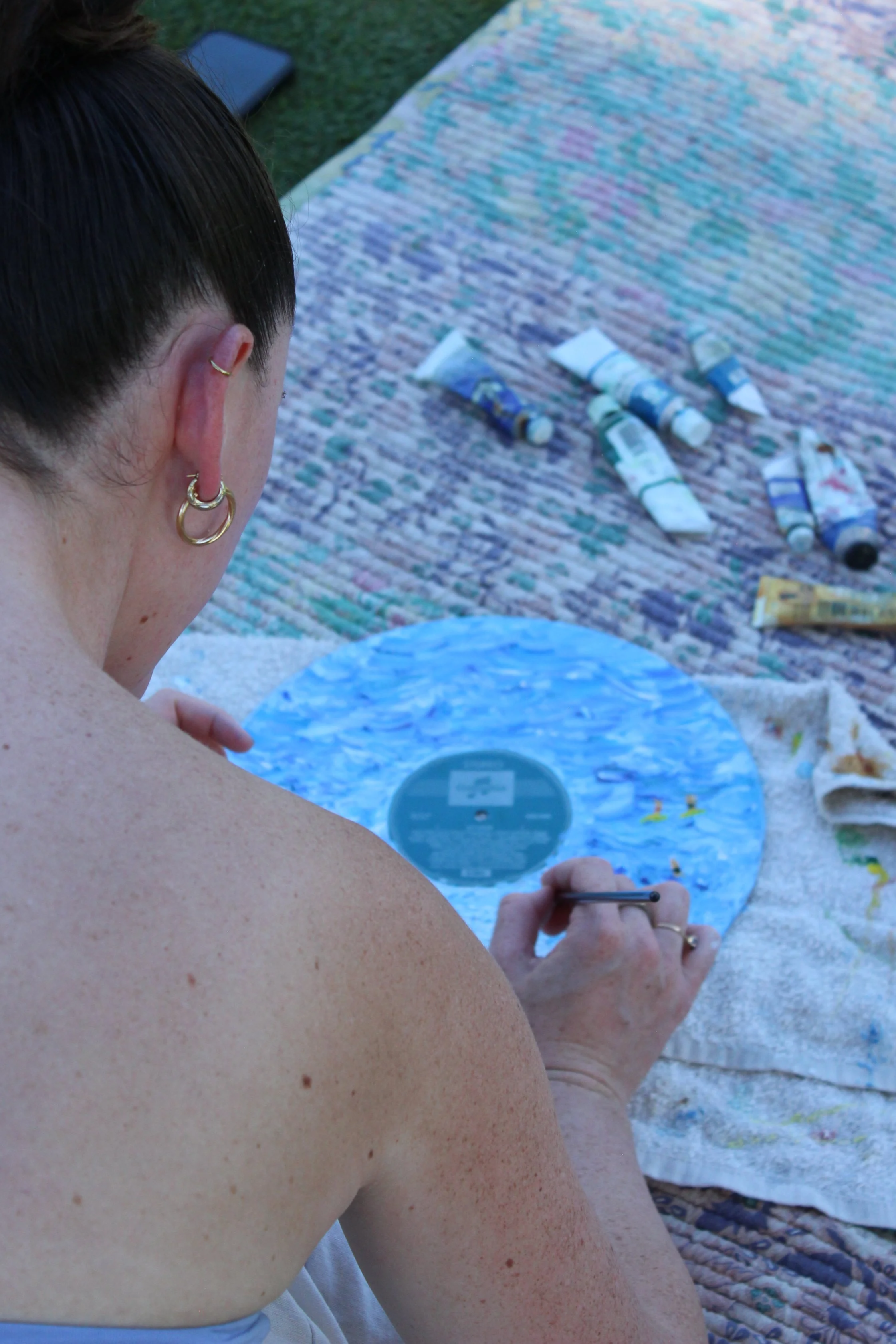 Close-up of a vinyl record being painted with oil paints during a guided outdoor workshop.