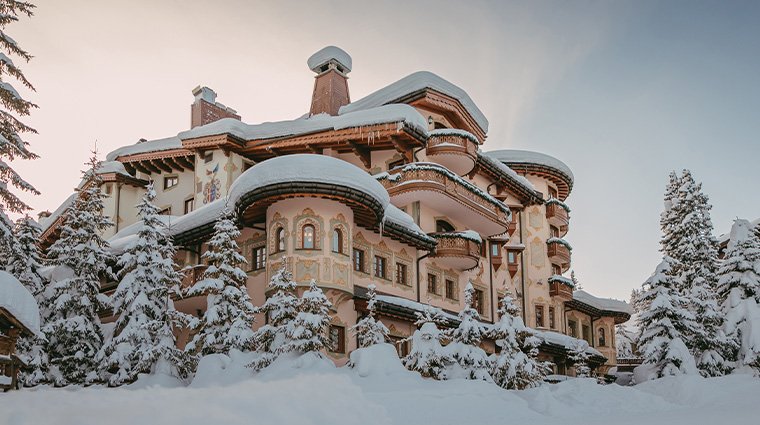 Large, ornate snow-covered mansion surrounded by snow-laden trees in winter