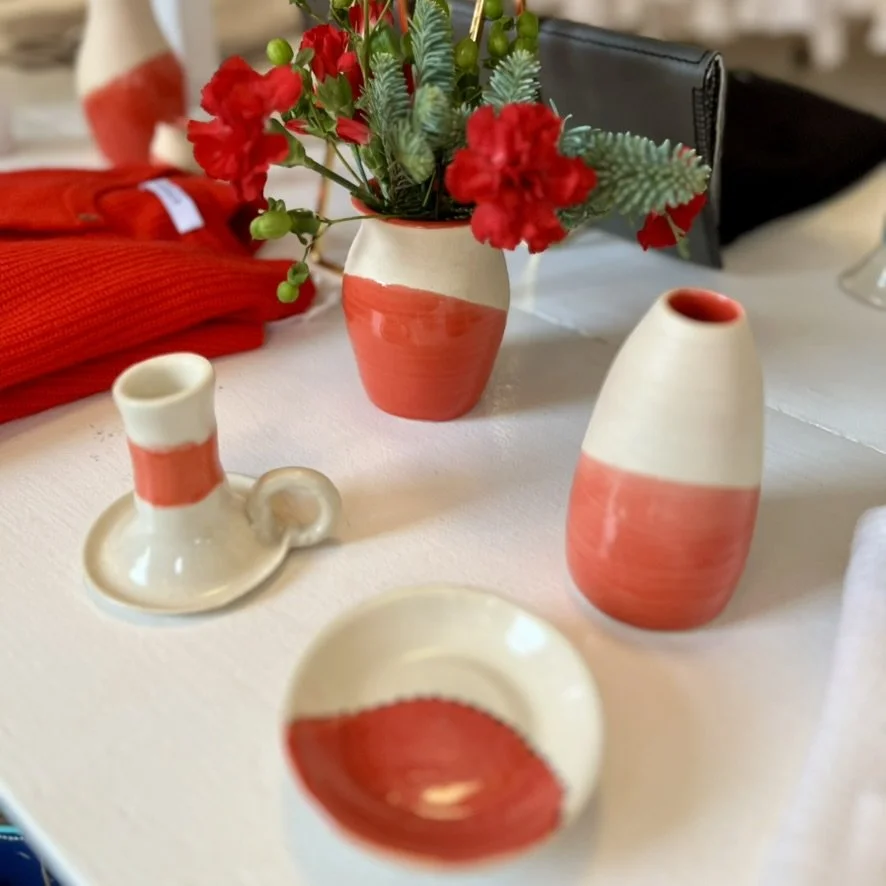 Decorative ceramic vases and a small bowl on a table, with a flower arrangement in a vase in the background.