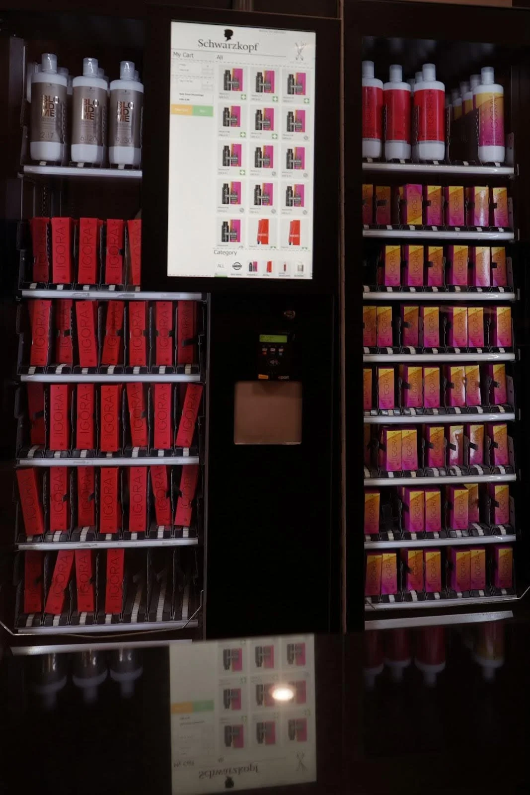 A vending machine with various hair care product bottles and boxed products, with a digital screen at the top displaying the store's catalog.