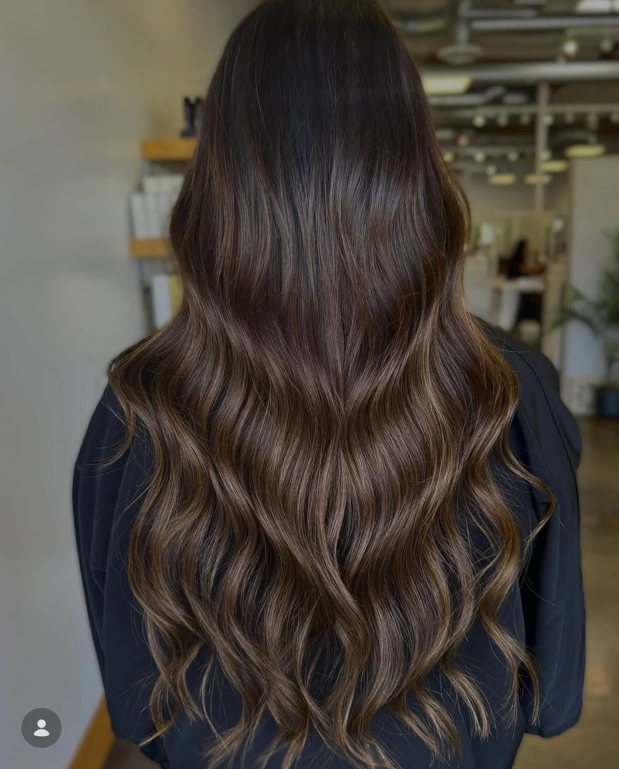 Back view of a woman with long, wavy, brown hair.
