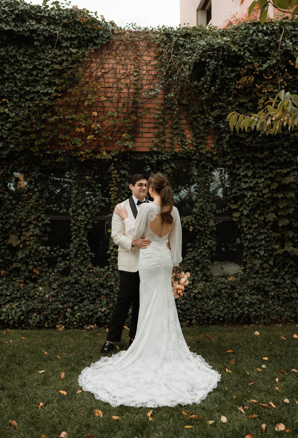 Bride and groom embracing before an ivy covered wall in New York