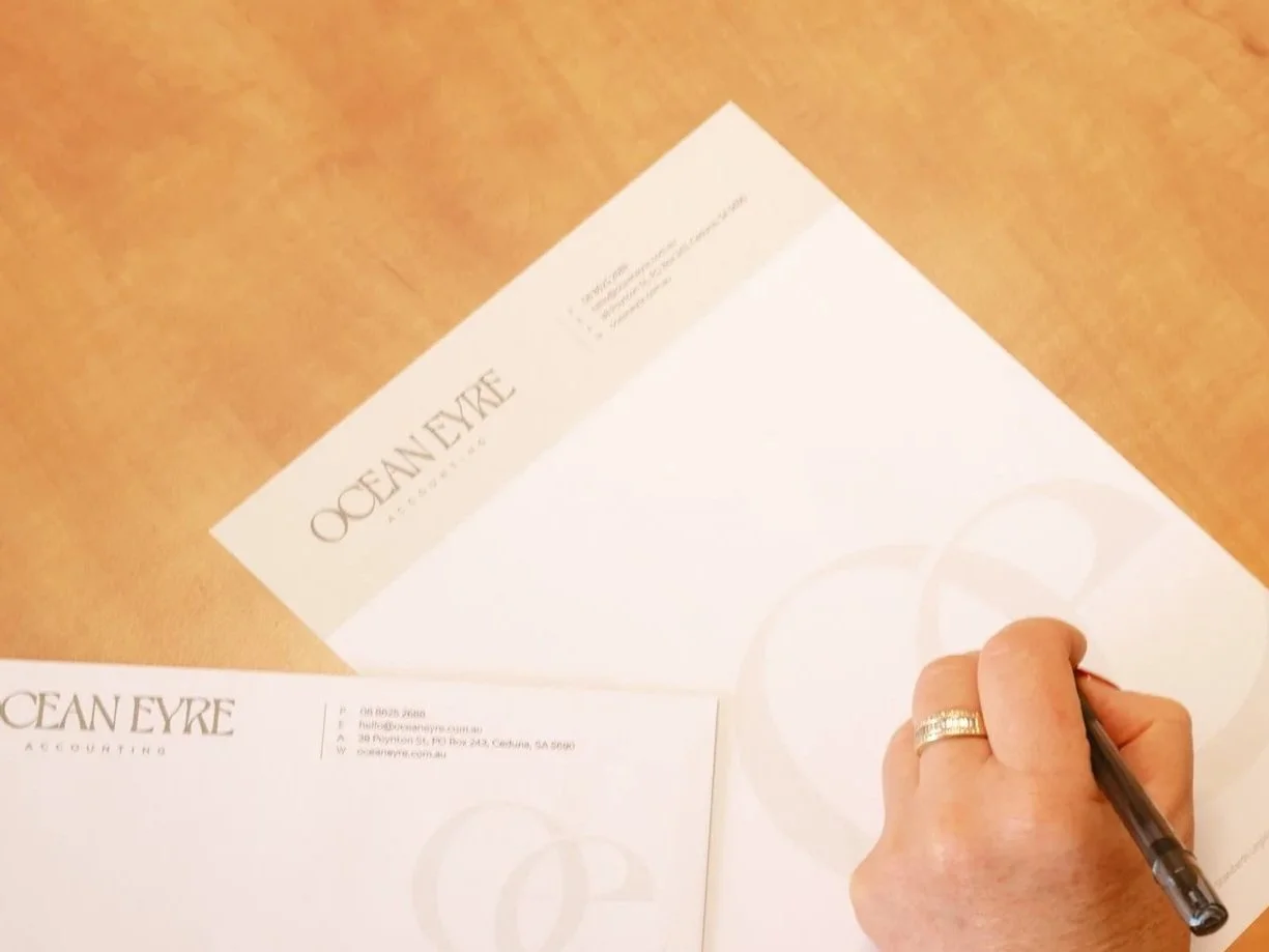 Stack of four binders filled with papers on a desk with a cup of coffee on a saucer and glasses.