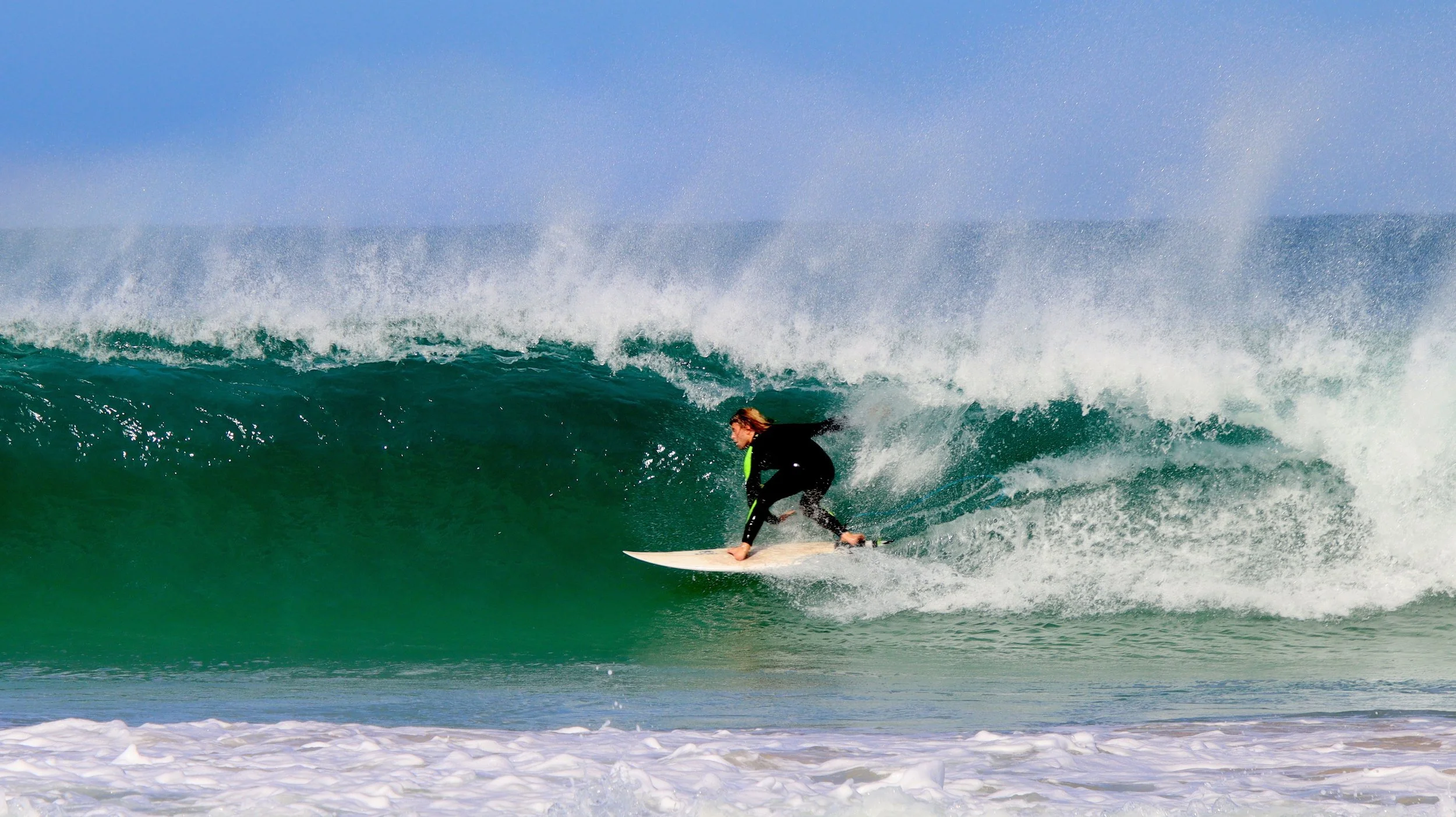 A woman surfing on a green wave at the beach during daytime.