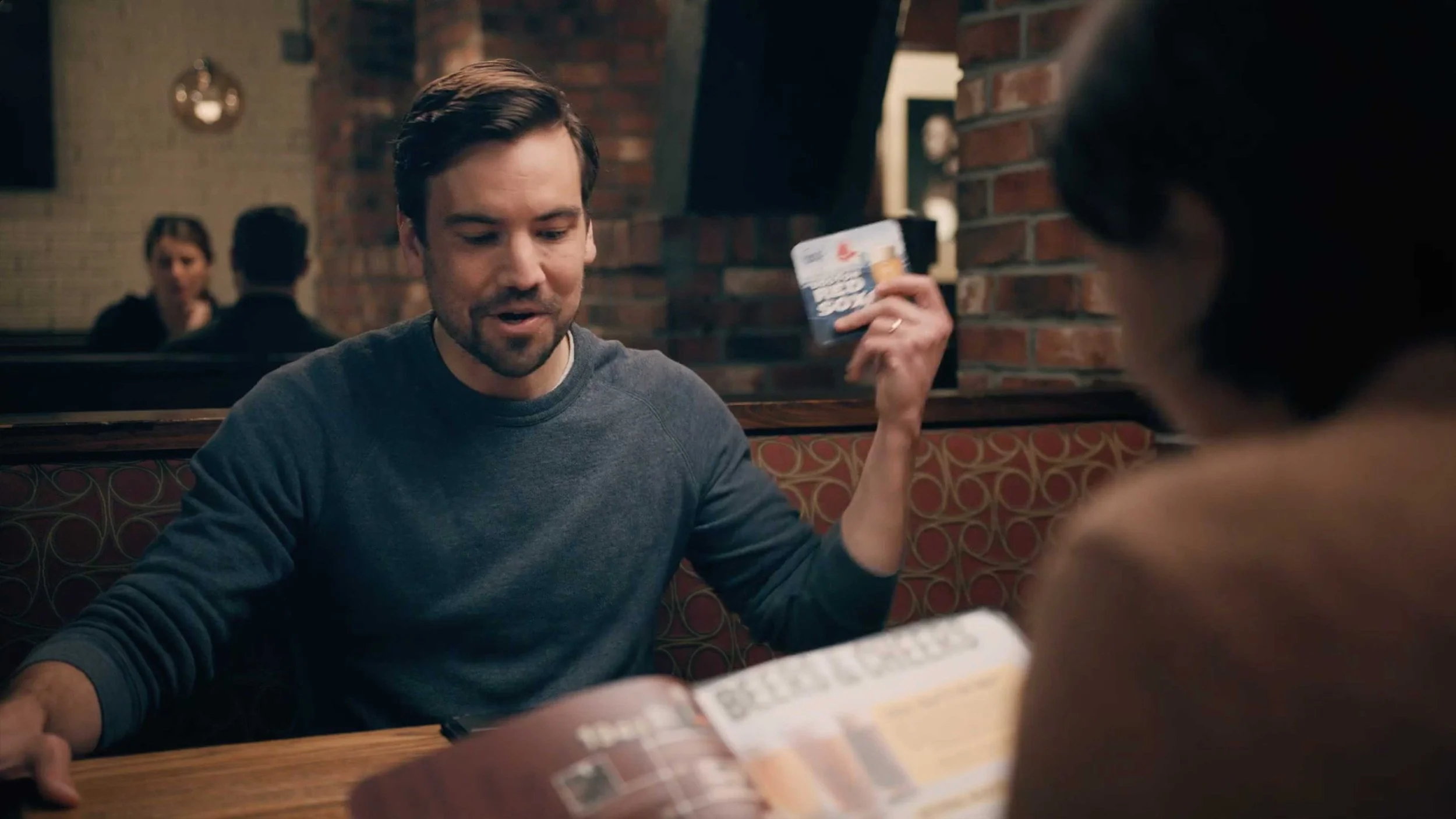 A man and woman sit in a restaurant preparing to order in an Unos commercial
