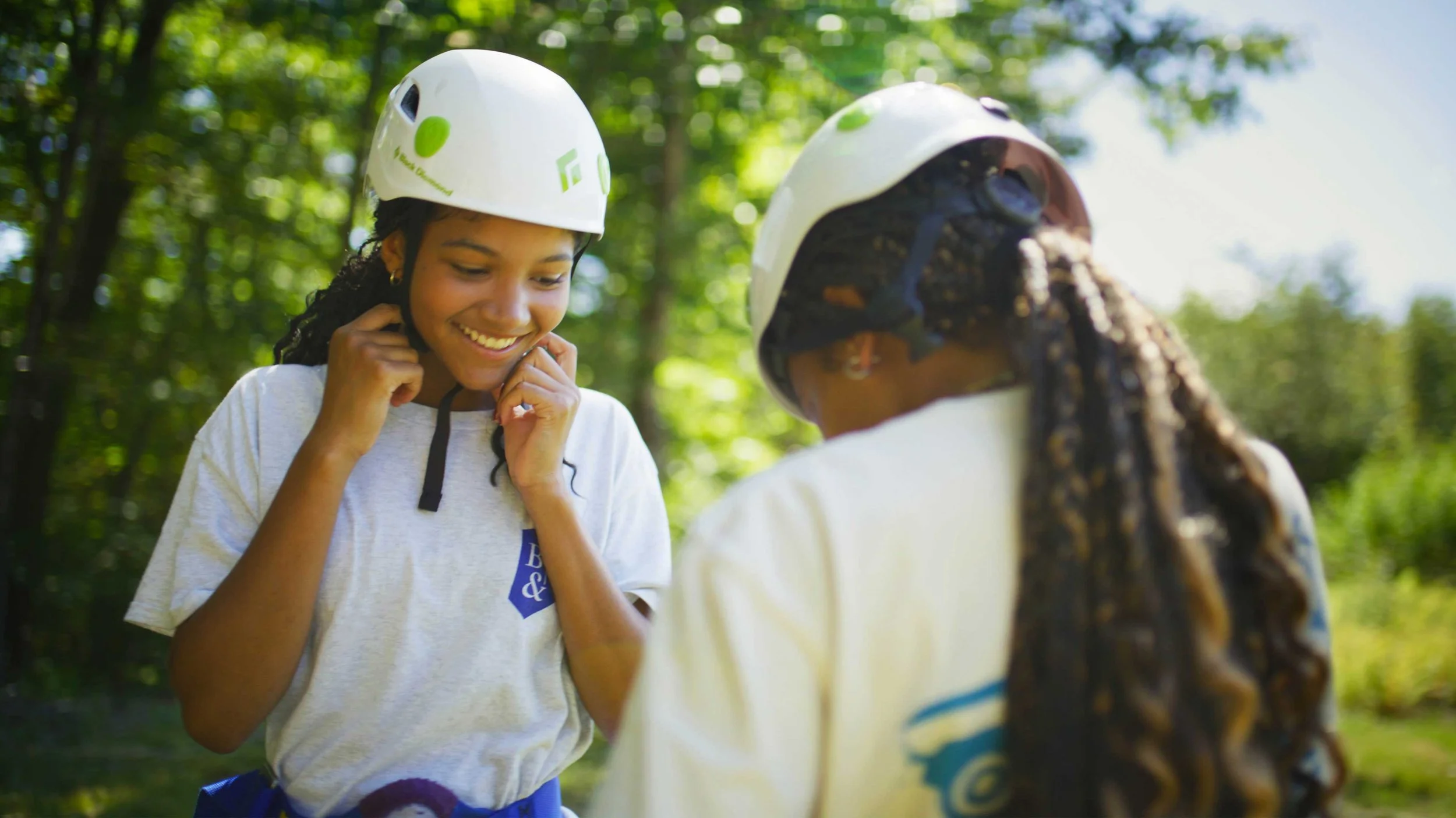 Two students putting on helmets for zip lining in Buckingham Browne & Nichols School’s Bivouac Documentary video