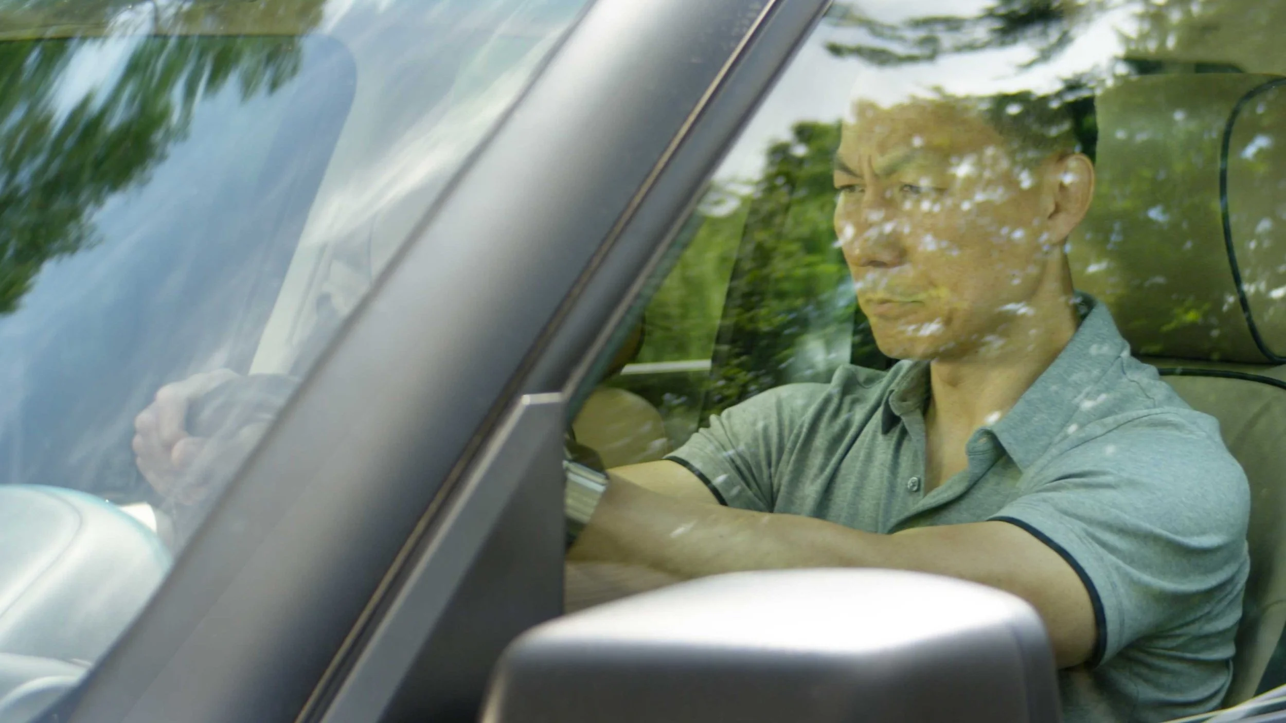 A man sitting in his car through the windshield in a patient testimonial video