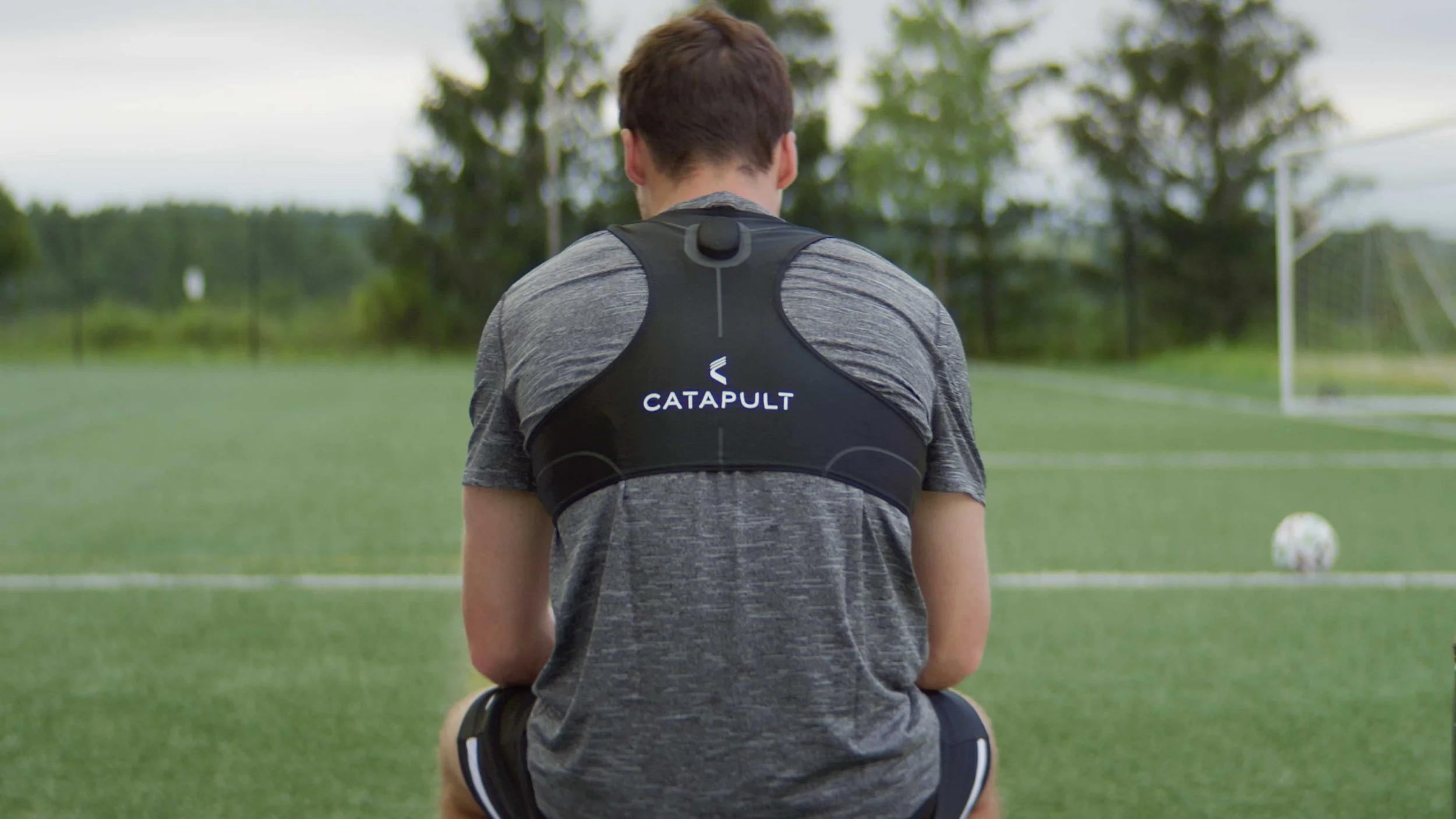 A teenage boy sits with his back to camera wearing a Catapult Sports tracking product in this video commercial