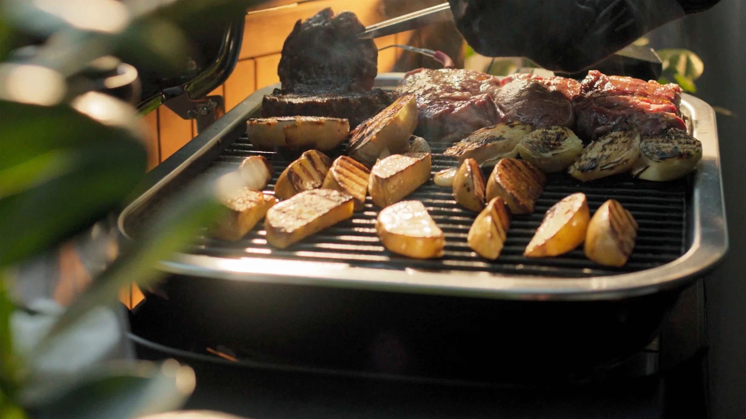 An electric grill with meat and vegetables in a video edited for BBQ Guys