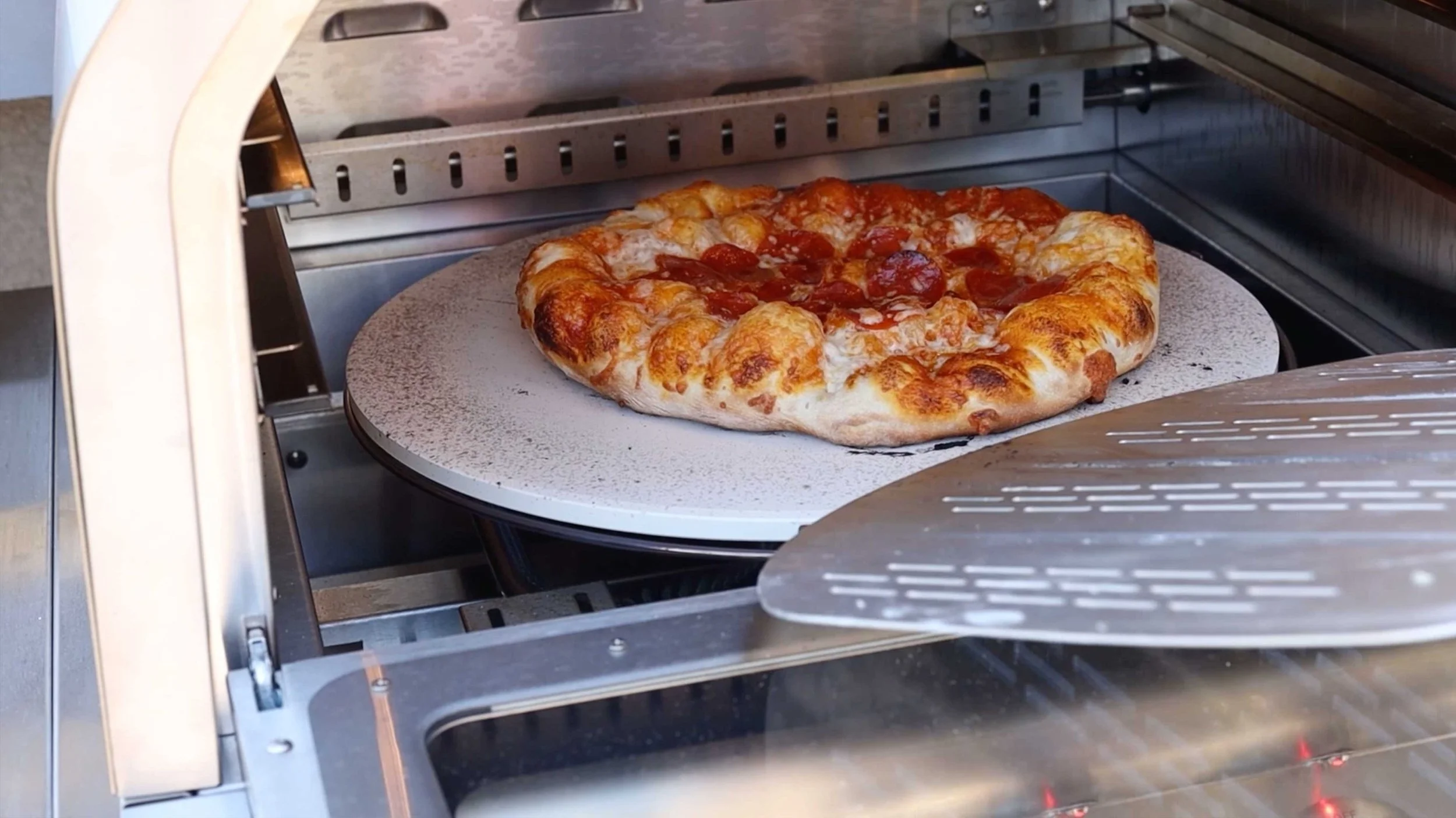A pizza coming out of an oven in a BBQ Guys expert review video
