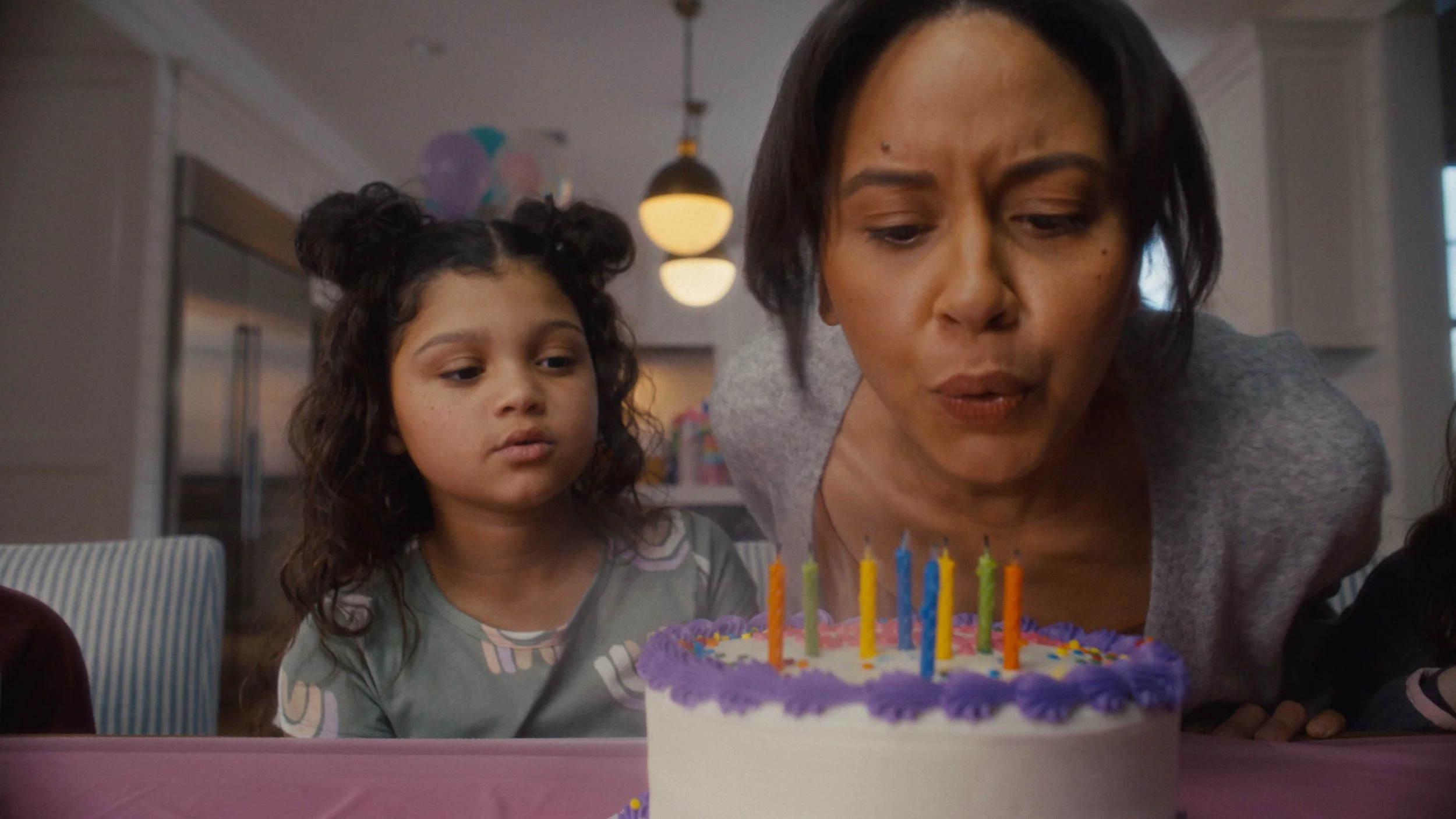 A woman blows out candles on a birthday cake in a commercial for Dynatrace