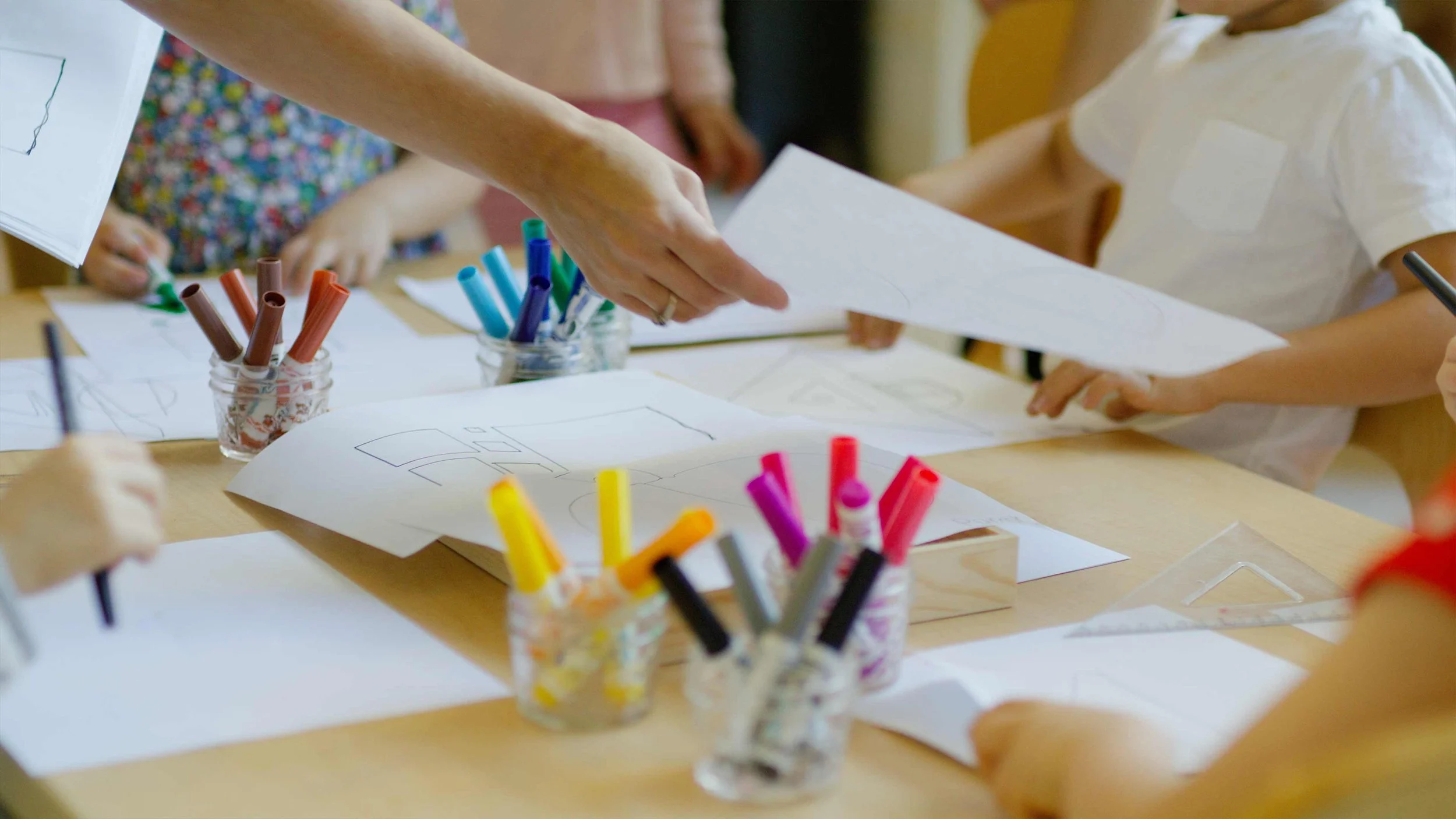A table with paper and various colored markers from a commercial video