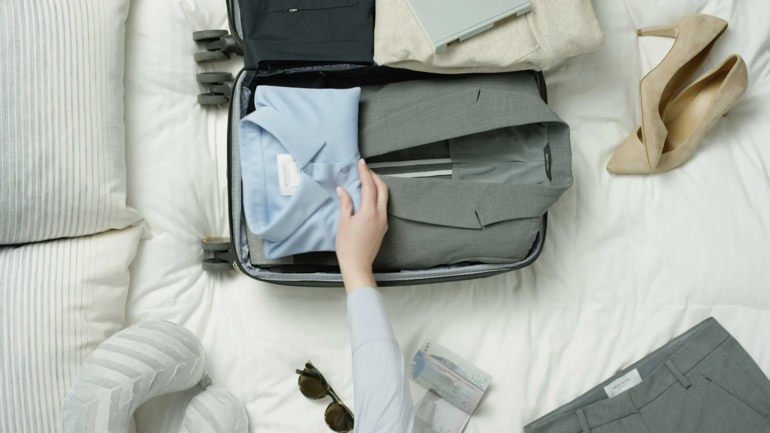 Person packing clothing and travel items for fashion lifestyle shoot