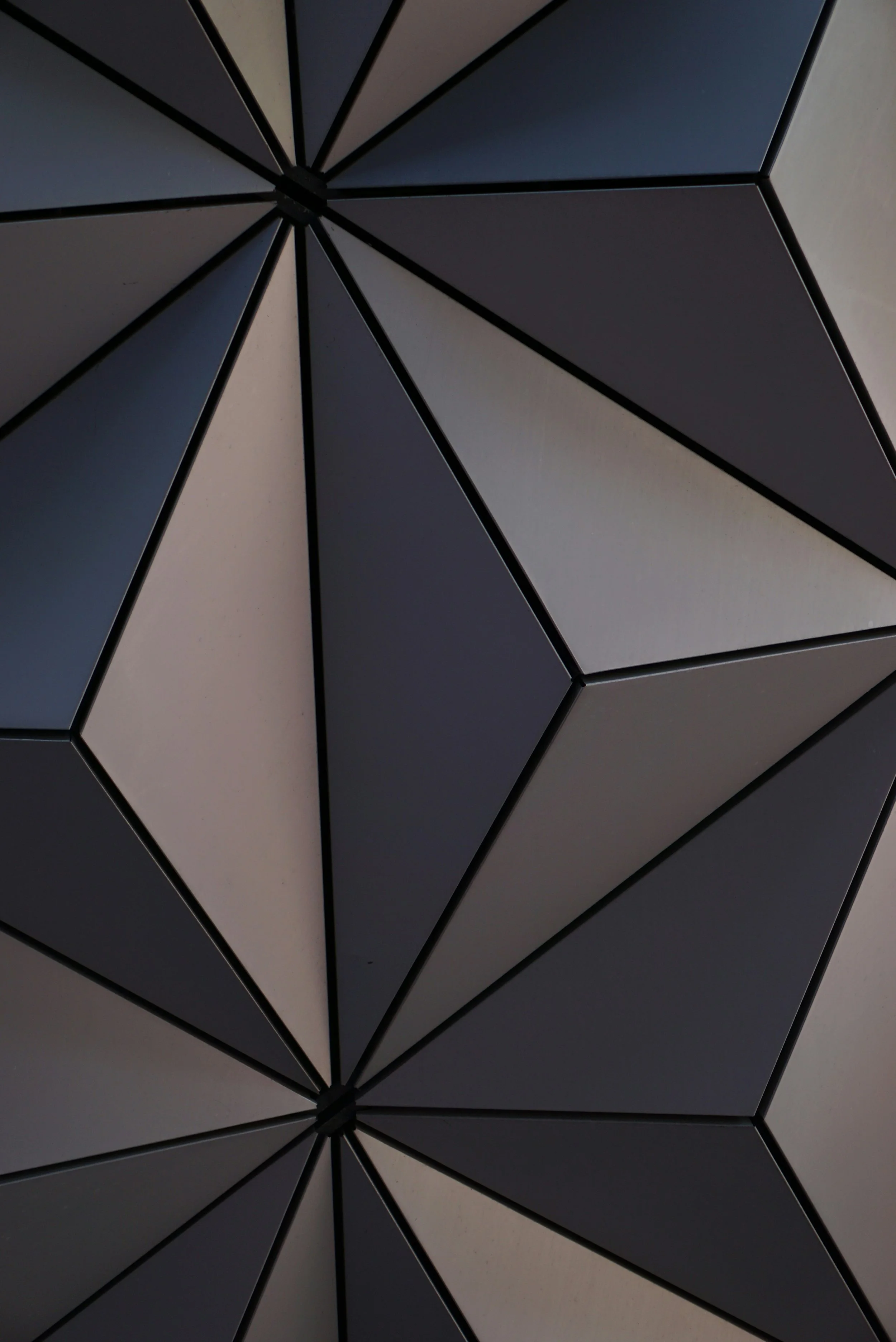 A modern, geometric ceiling with black and white triangular panels arranged in a starburst pattern.