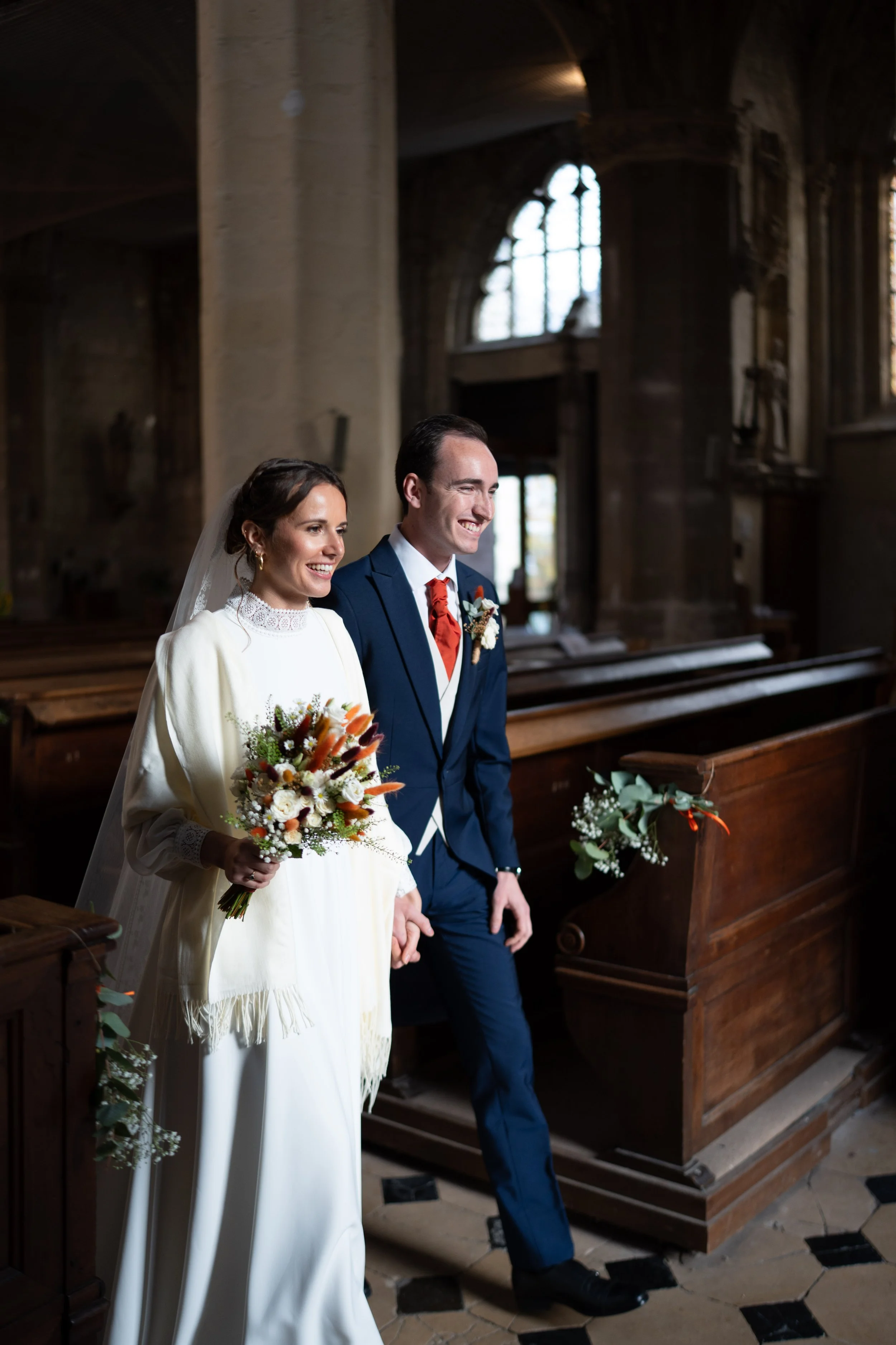 Un couple de mariés heureux dans une église en bois, en train de se tenir la main lors de leur mariage.