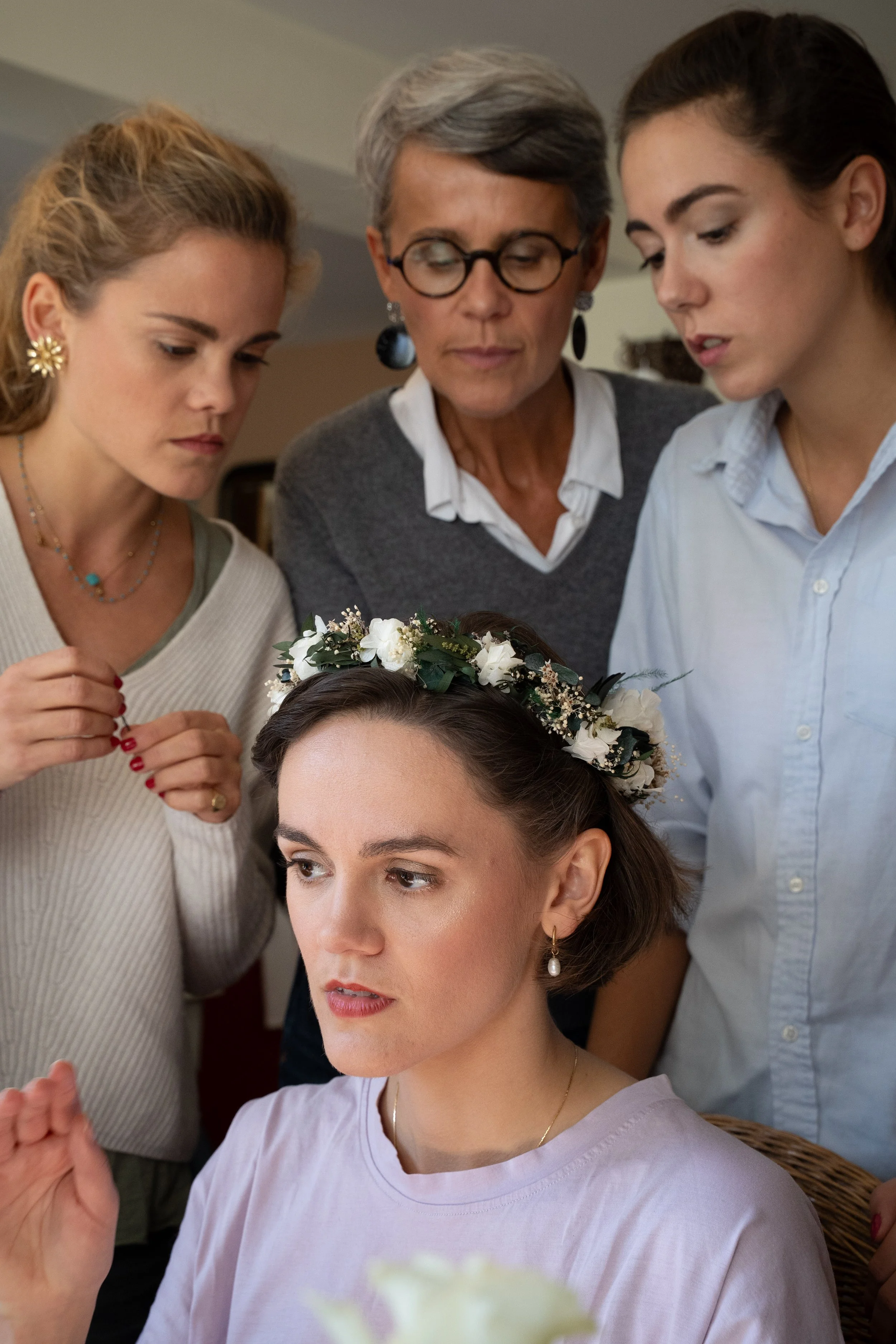 Groupe de femmes, probablement lors d'une cérémonie, avec une femme portant une couronne de fleurs sur la tête, qui semble être le centre de l'attention.