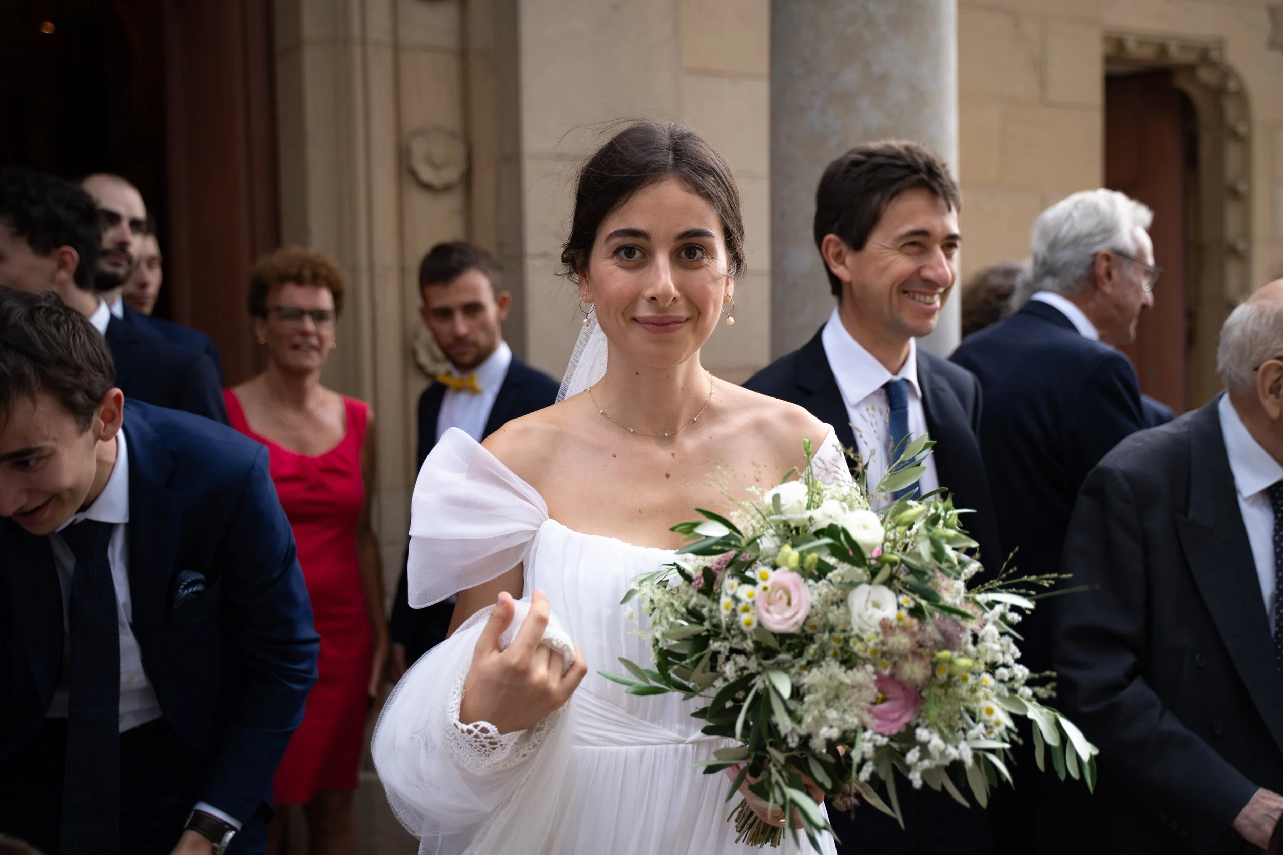 Une femme en robe de mariée tenant un bouquet de fleurs lors d'une cérémonie dans une église.