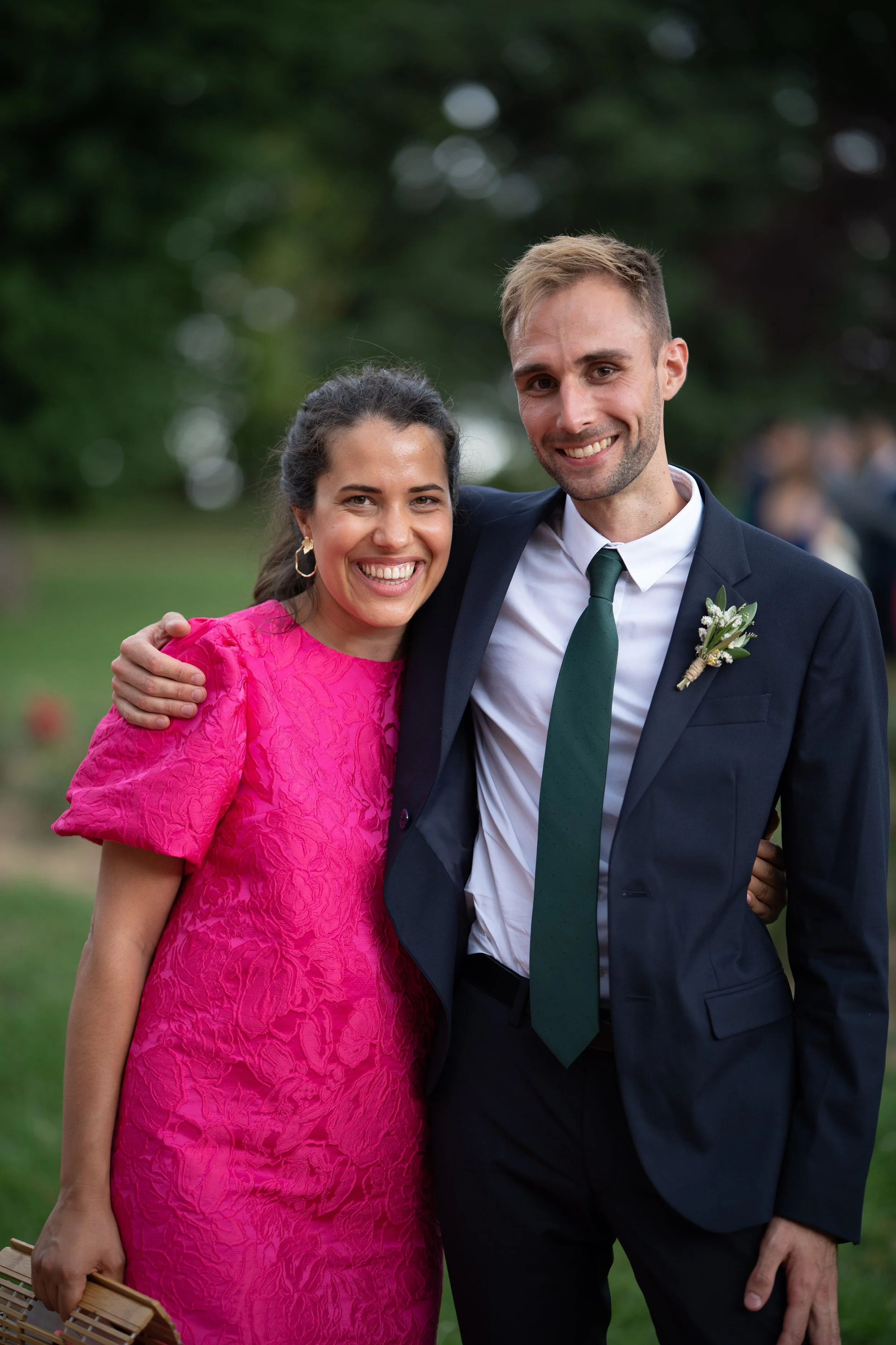 Un homme et une femme souriants, habillés de manière élégante, se tiennent ensemble à l'extérieur lors d'un événement ou d'une célébration.