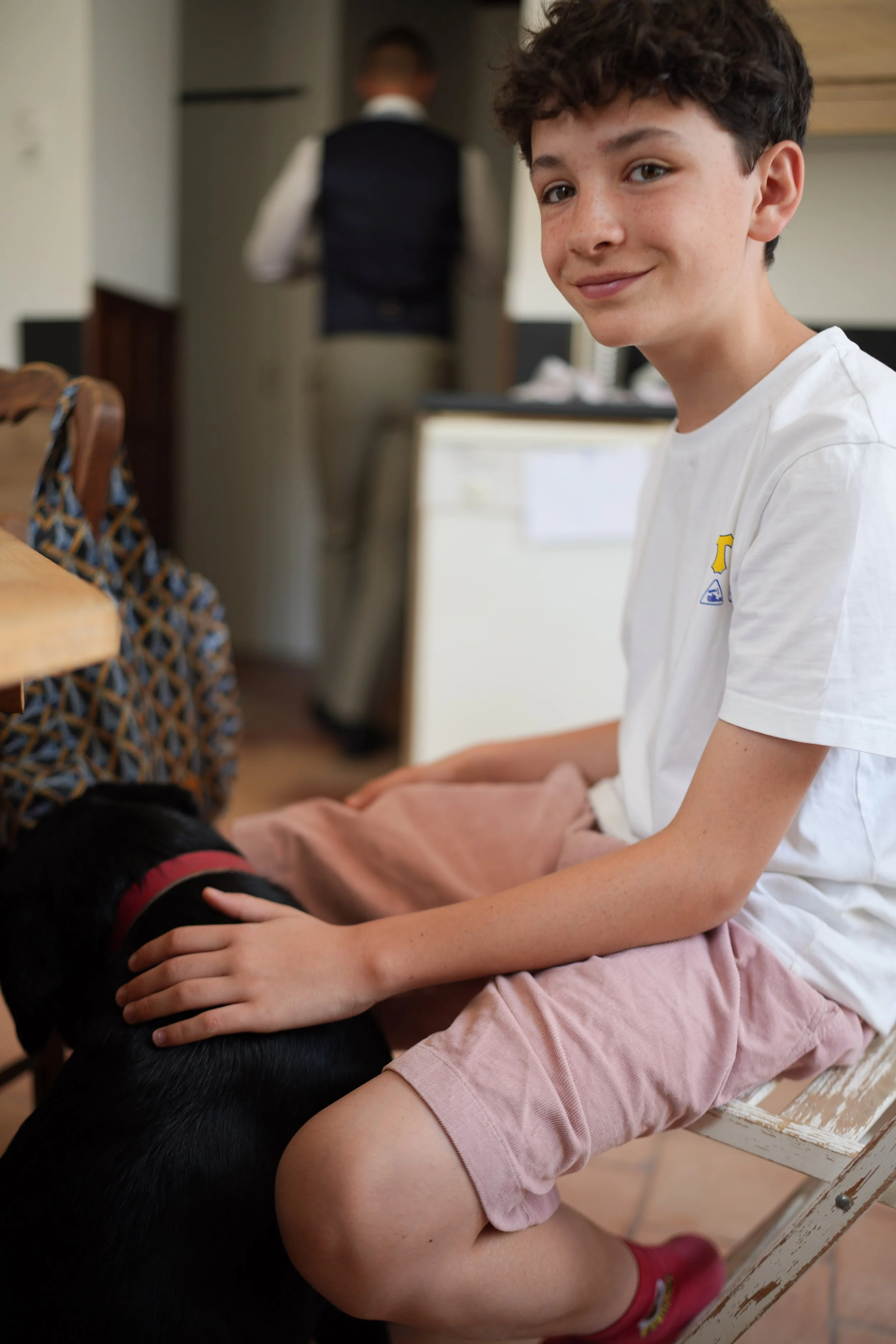 Une jeune fille assise sur une chaise avec un chien noir, les deux personnes se touchent la tête.