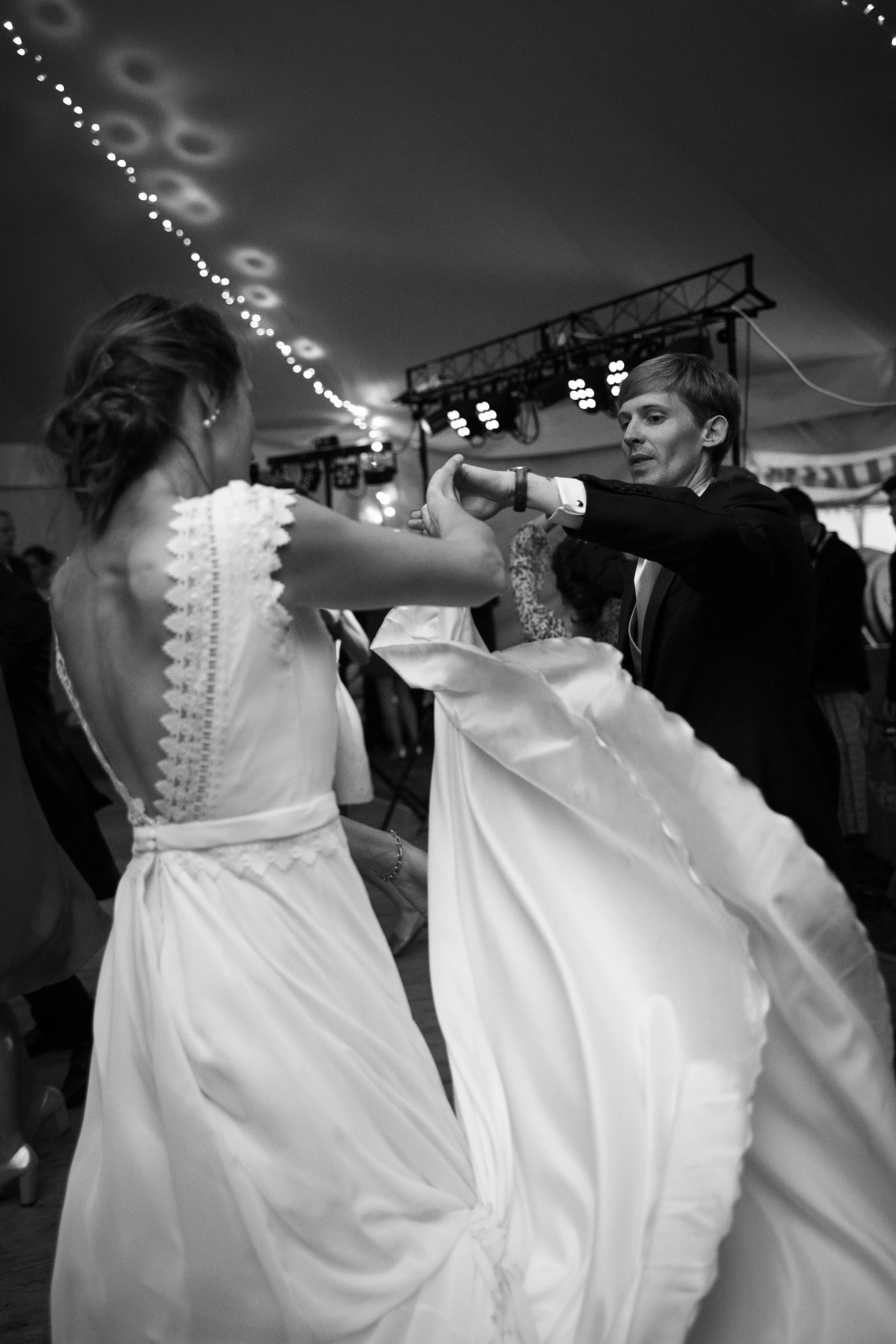 Homme et femme dansant lors d'une fête ou d'une réception, la femme porte une robe de mariée et l'homme un costume, ambiance festive avec décorations et éclairage