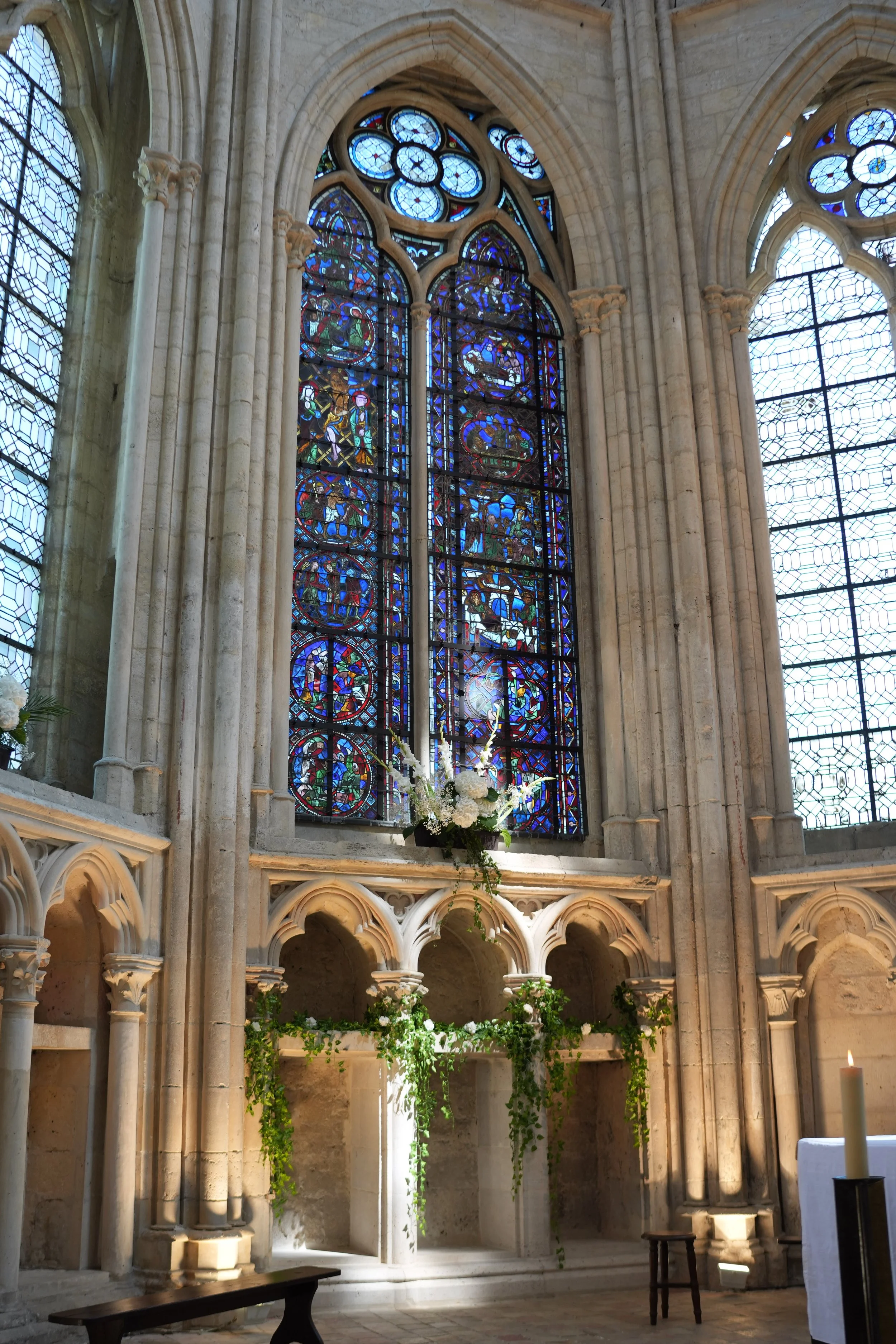 Vitraux colorés représentant des scènes religieuses, dans une église catholique gothique, avec des colonnes en pierre et une architecture typique.