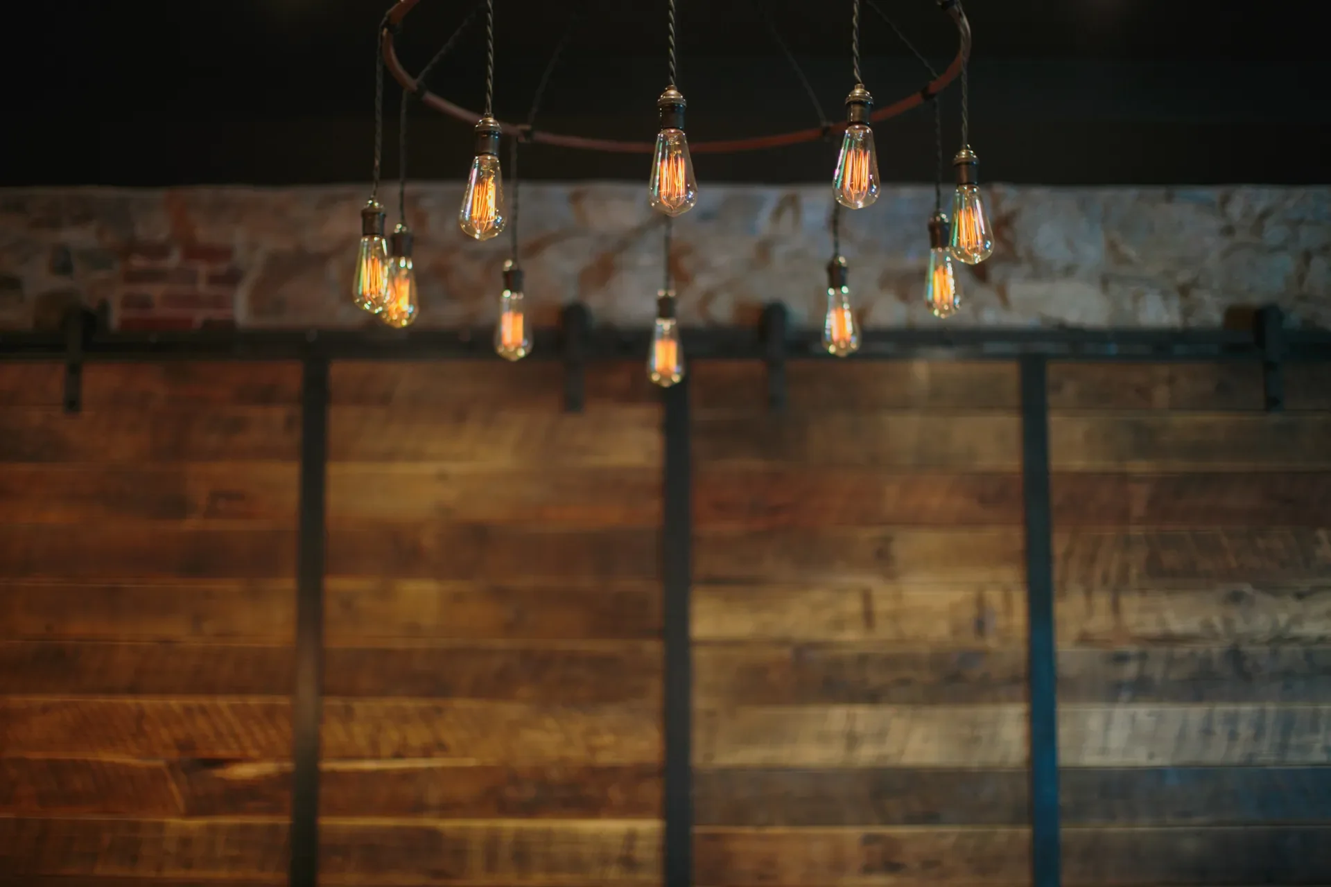 Ceiling with hanging Edison-style filament light bulbs in a rustic interior with wooden wall and brick accents.