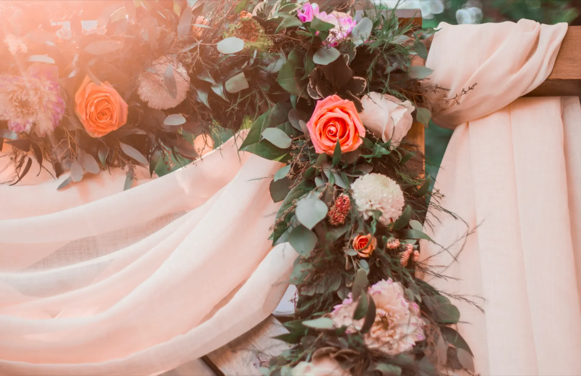 A floral arrangement on a table with soft pink fabric draped on the sides.