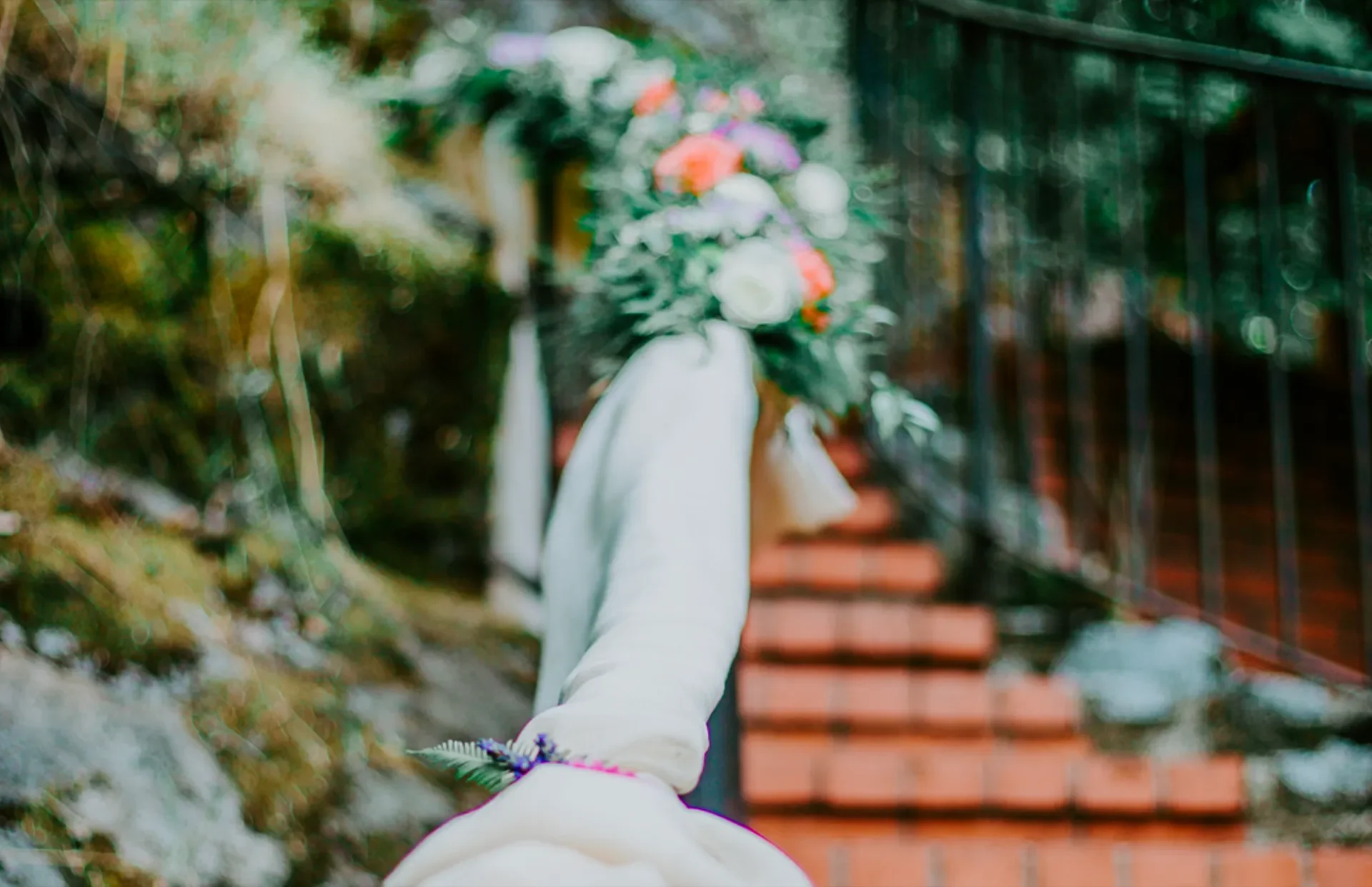 A bouquet of colorful flowers held by a person on a staircase outdoors.