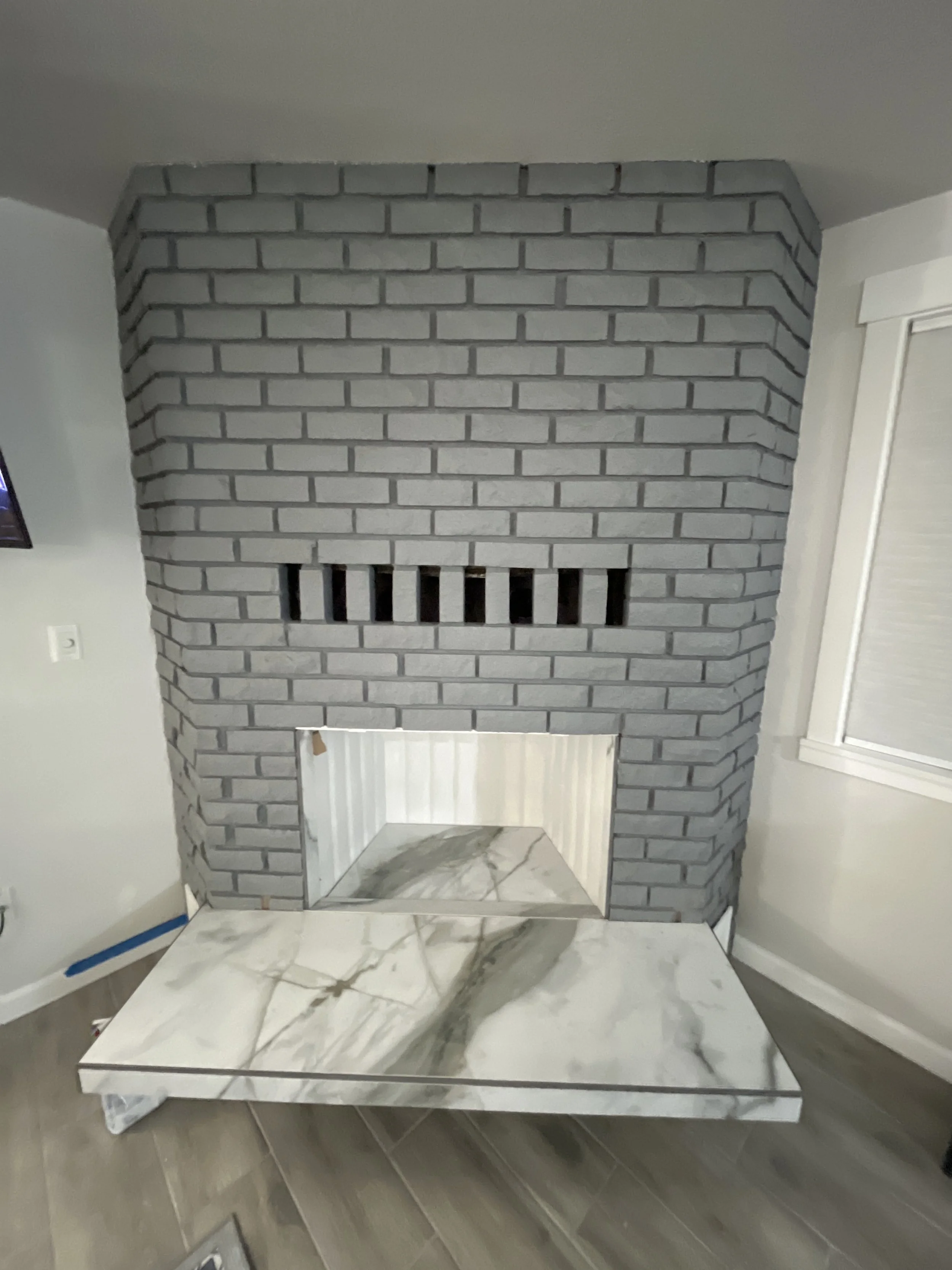 Indoor fireplace with gray brick surround, small opening, and a marble slab hearth.