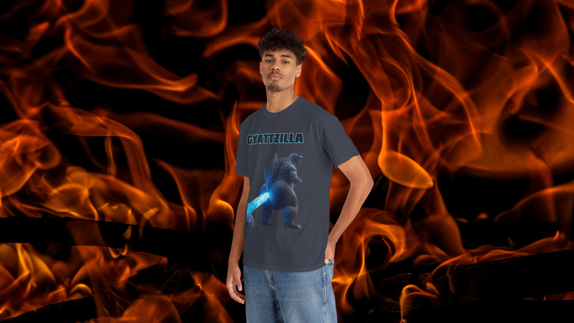 A young man wearing a gray T-shirt with the word 'GYATTZILLA' and a graphic of Godzilla, standing in front of a background of flames.