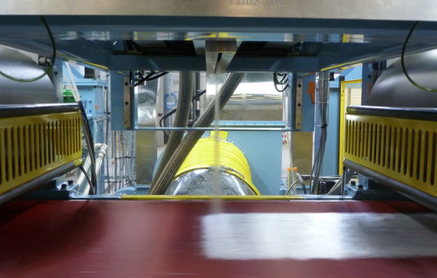 Industrial machinery with yellow and blue components and a large metal pipe or tunnel in the center, viewed from below.