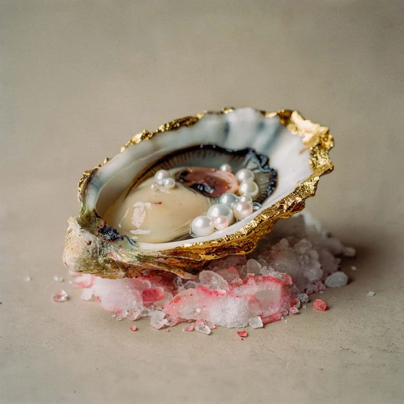 Una conchiglia decorativa con perle e elementi decorativi, appoggiata su una base di sale rosa e sale traslucido sulla superficie