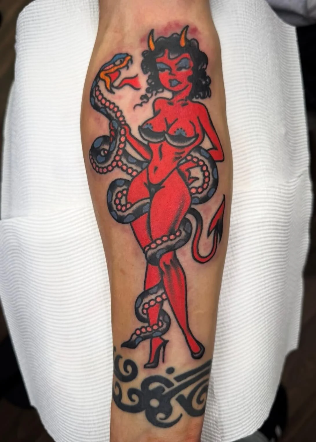 Masculine arm tattoo of devil pinup girl and snake