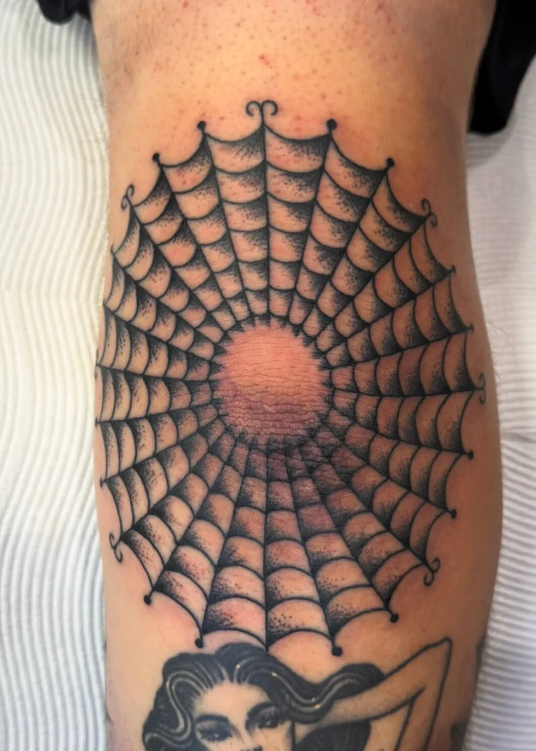 Tattoo of a detailed spider web pattern on a person's side ribcage, with the sun in the center.