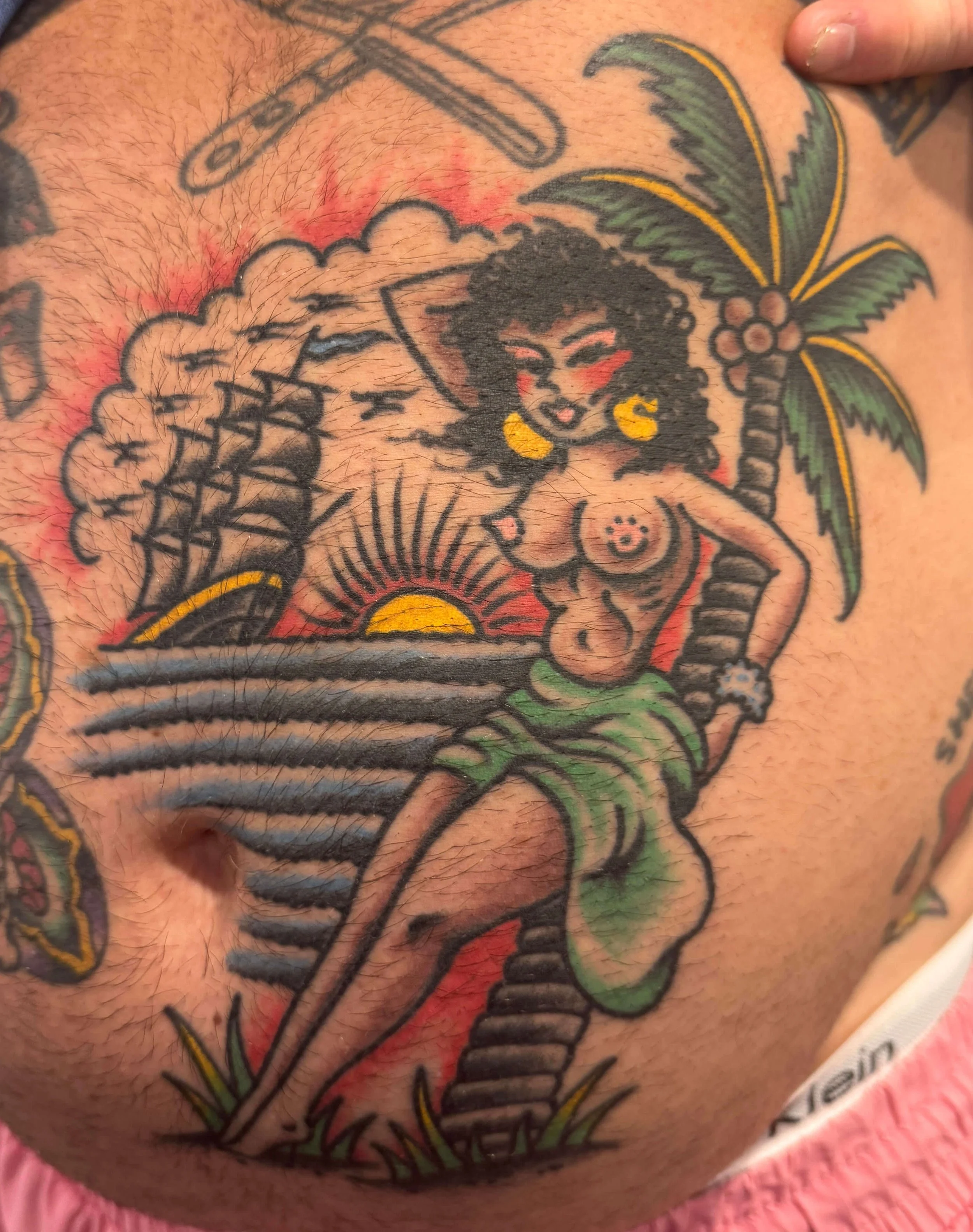 Healed bold and bright tattoo of hula gir with ship on torso