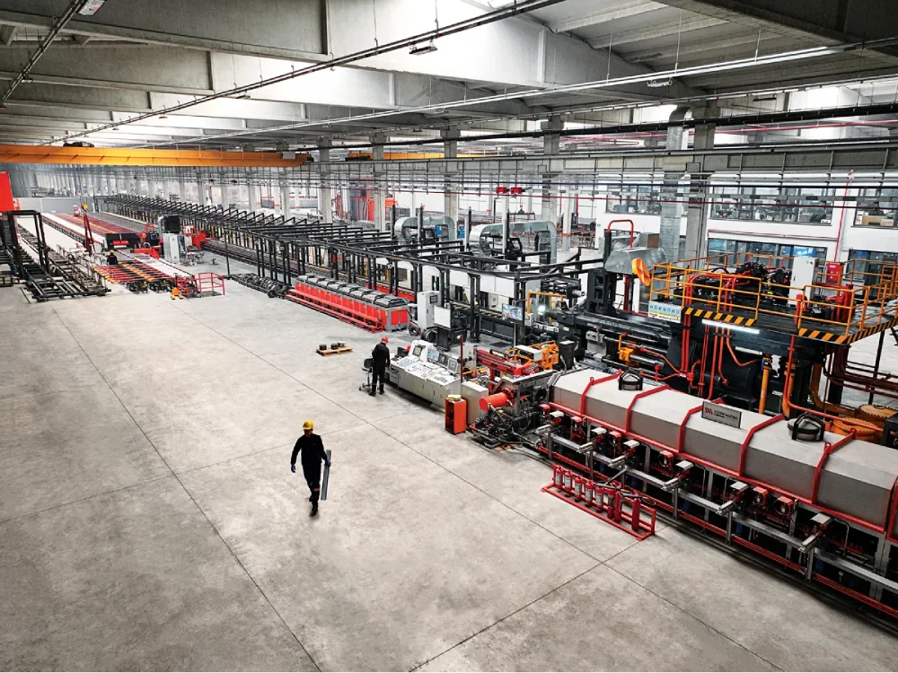 Interior view of an industrial manufacturing facility with large machinery, conveyor belts, and workers inspecting equipment.