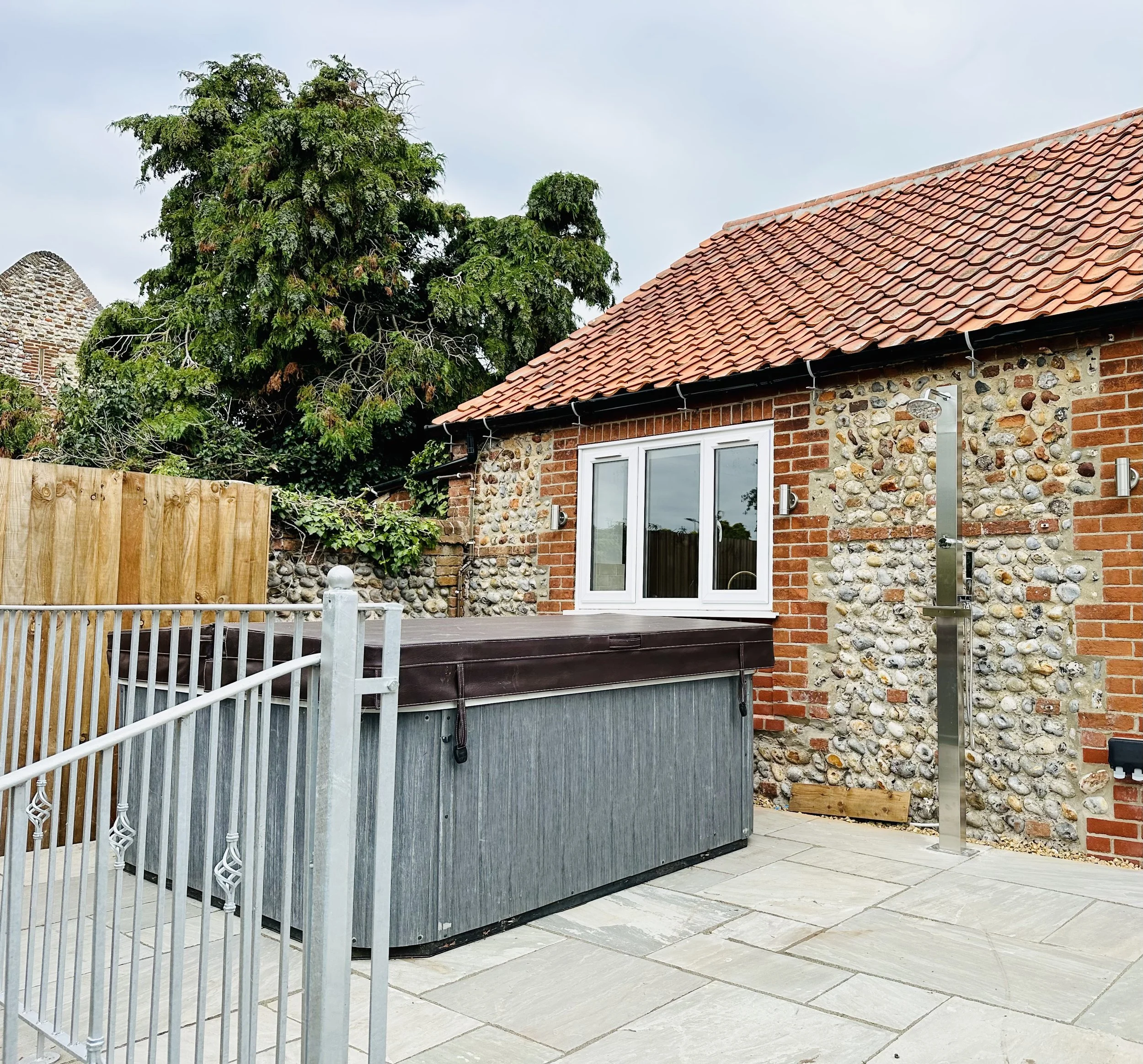 Large garden terrace with hot tub and outdoor shower, the perfect place to wash off and wind down after a day at the beach