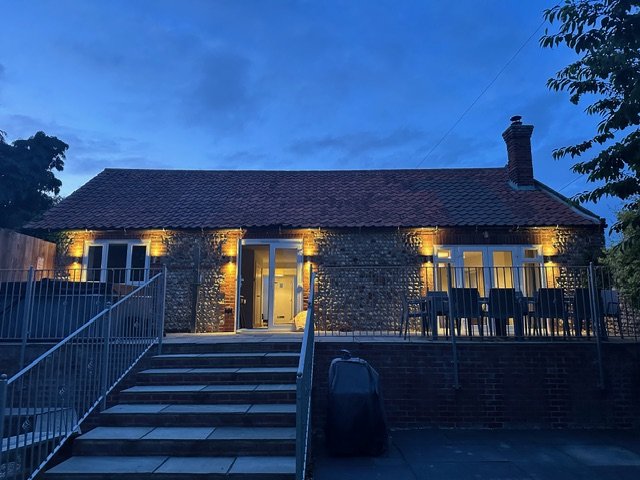 Enjoy some alfresco dining with the whole family on this beautiful garden terrace, a staircase leading up to the door to the kitchen, and a patio with a dining table and chairs.