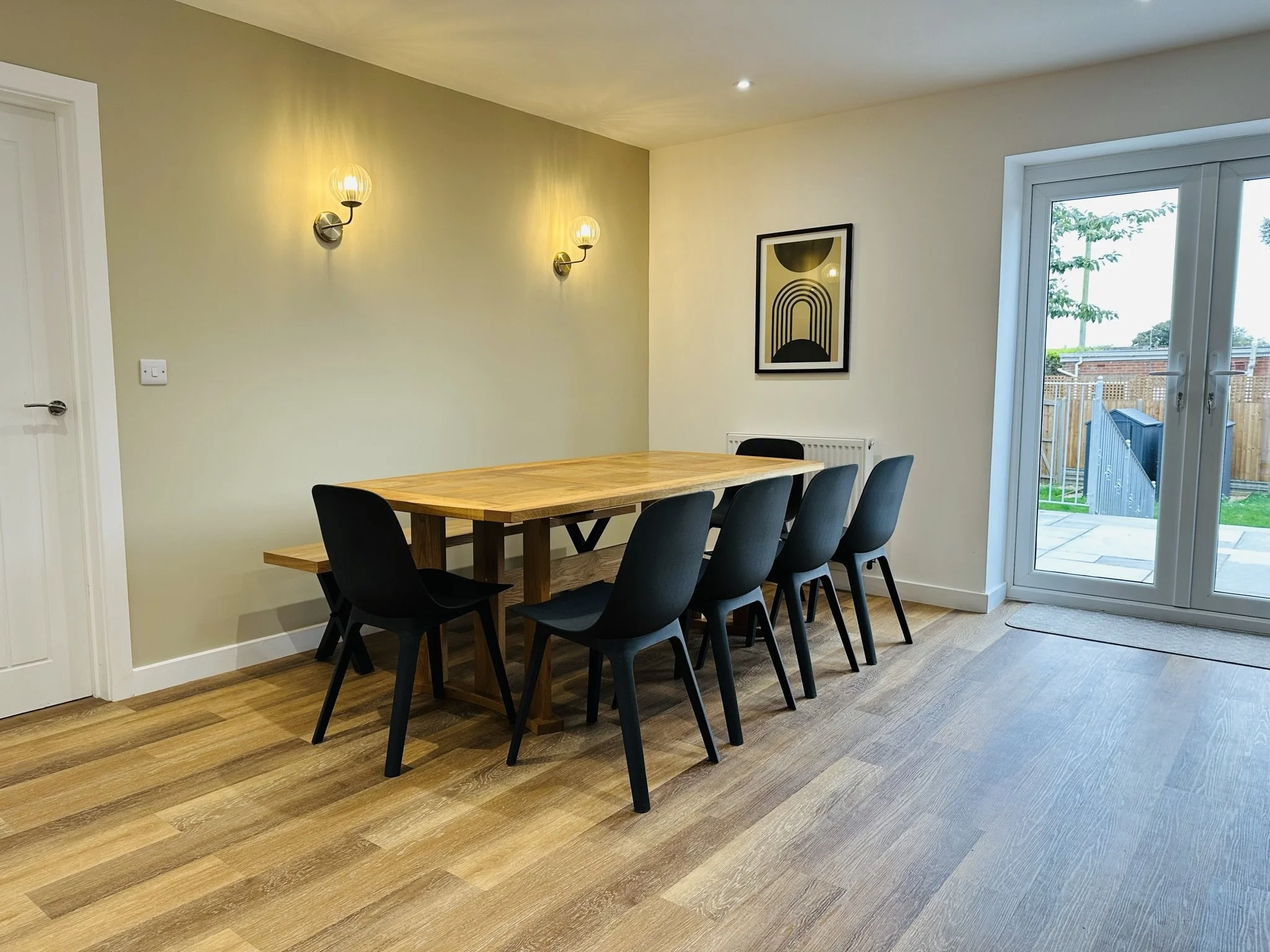 Spacious dining room in Bacton North Norfolk with a wooden table to seat 10 people on holiday together with large french doors leading out onto garden terrace, hot tub and large lawn