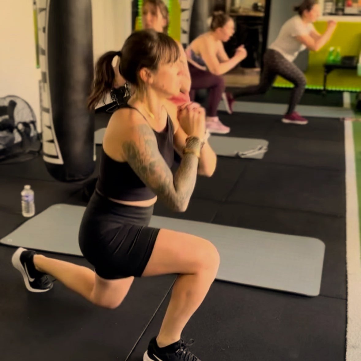 Une femme effectuant un exercice de squat dans une salle de sport avec d'autres personnes en arrière-plan