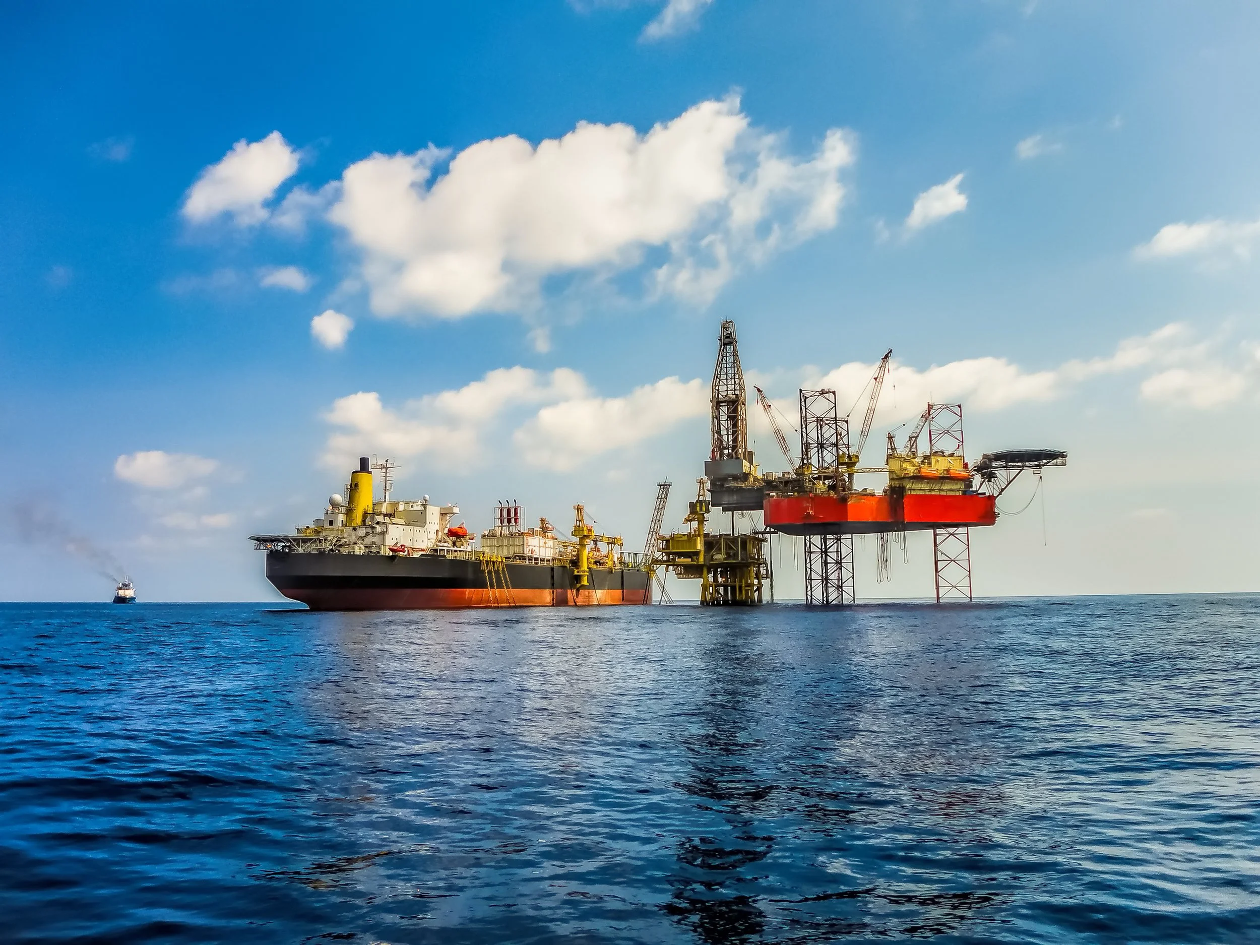 Offshore oil drilling platform in the ocean under a partly cloudy sky.