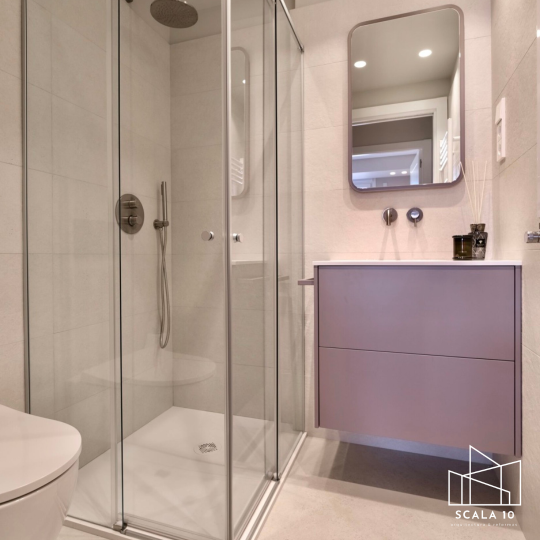 Baño moderno con ducha de vidrio, espejo y mueble con lavamanos.