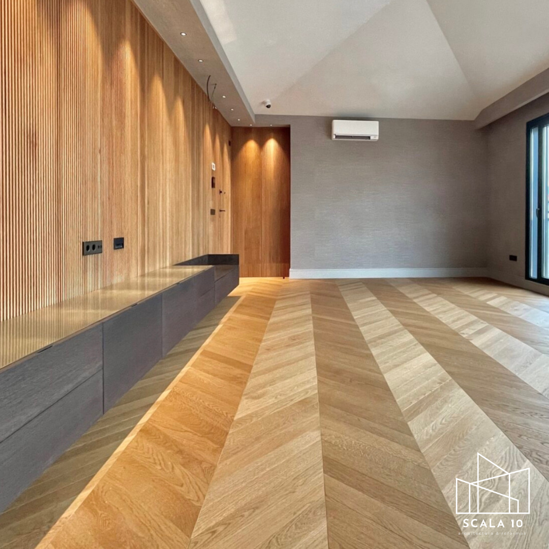 Sala moderna con paredes de madera y grises, piso de madera en patrón diagonal, ventana grande y aire acondicionado en la pared.