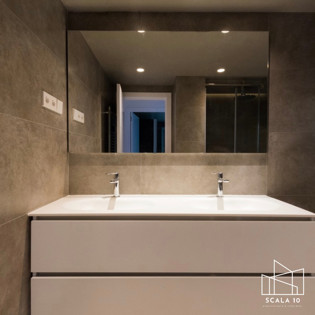 Lavabo doble con espejo grande en un baño moderno con paredes de baldosas gris oscuro.