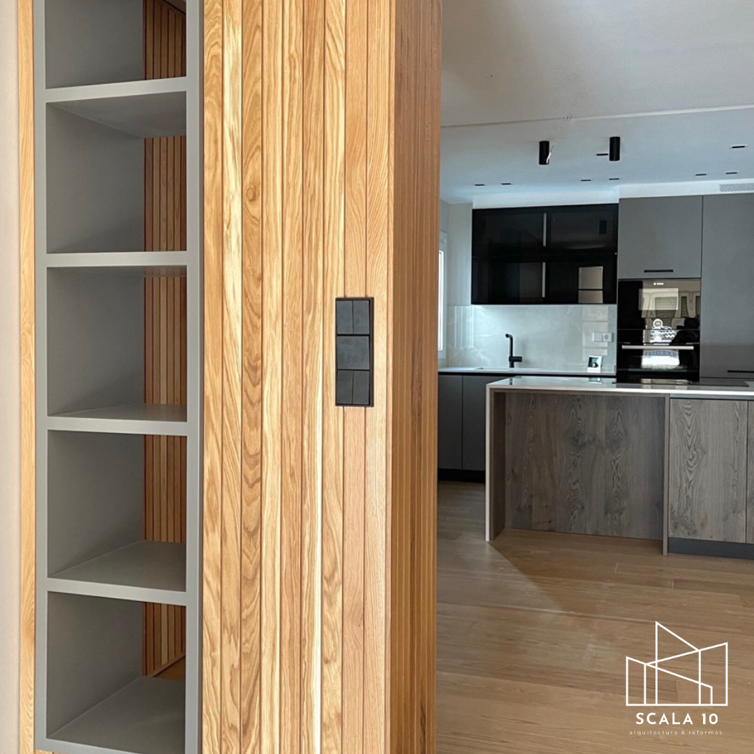 Vista de interior de una casa moderna con comedor y cocina, madera y tonos neutros.