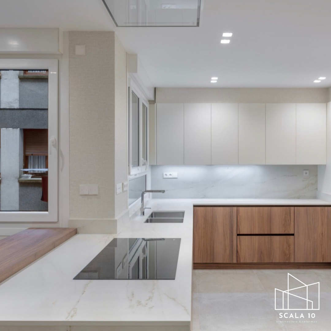Interiores de una cocina moderna con paredes claras, una pared de cristal con marco negro que divide espacios, armario empotrado y suelo de baldosas claras.
