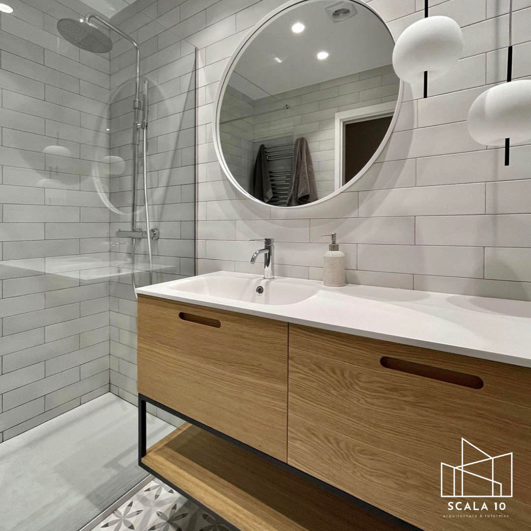 Baño moderno con paredes de azulejos blancos, lavabo de madera con espejo redondo y luz colgante